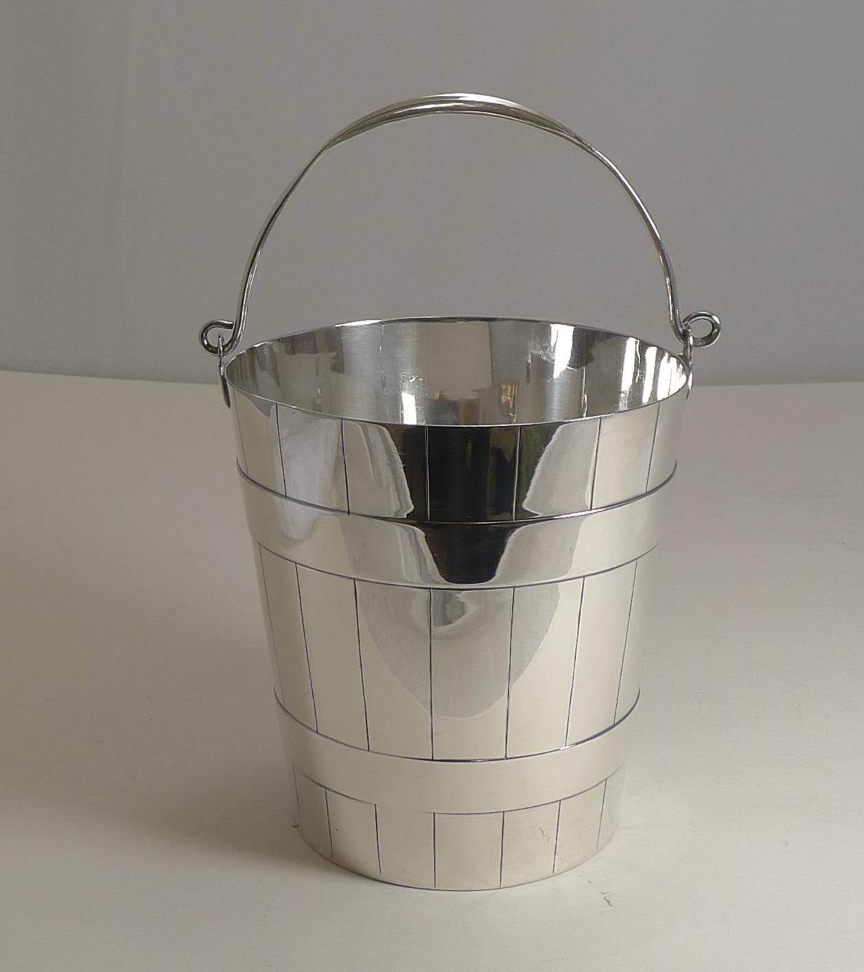 A handsome ice bucket or pail, in the form of a coopered bucket with a folding swing handle.

The original drainer is intact, sitting inside on a little ridge allowing any melted ice to fall through to the base, keeping the ice dry.

The