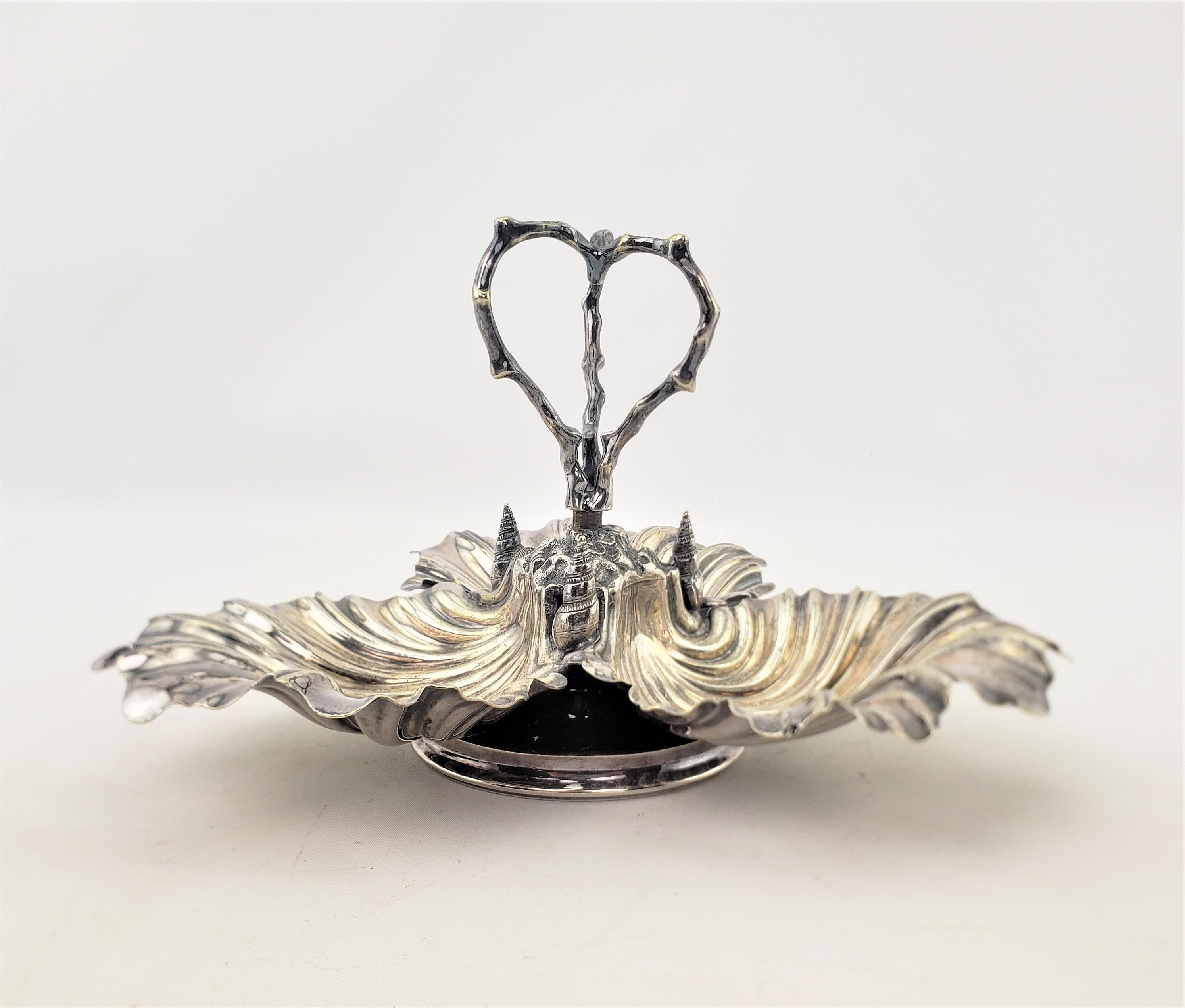 This antique serving dish is hallmarked by an unknown English maker, and believed to date to approximately 1910-1920 and done in a Victorian style. The dish is composed of copper with a silver plated finish and has three partitions using figural