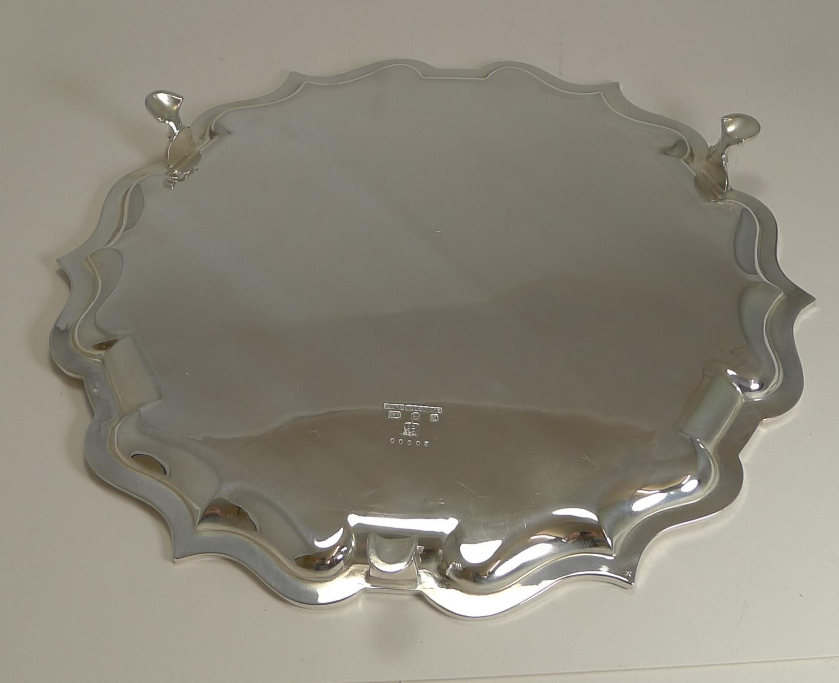 A beautiful and elegant antique English serving salver or drinks tray, beautifully shaped with a plain polished surface and standing on three legs.

The tray is made and fully marked for the top-notch silversmith, Elkington and Co.; being
