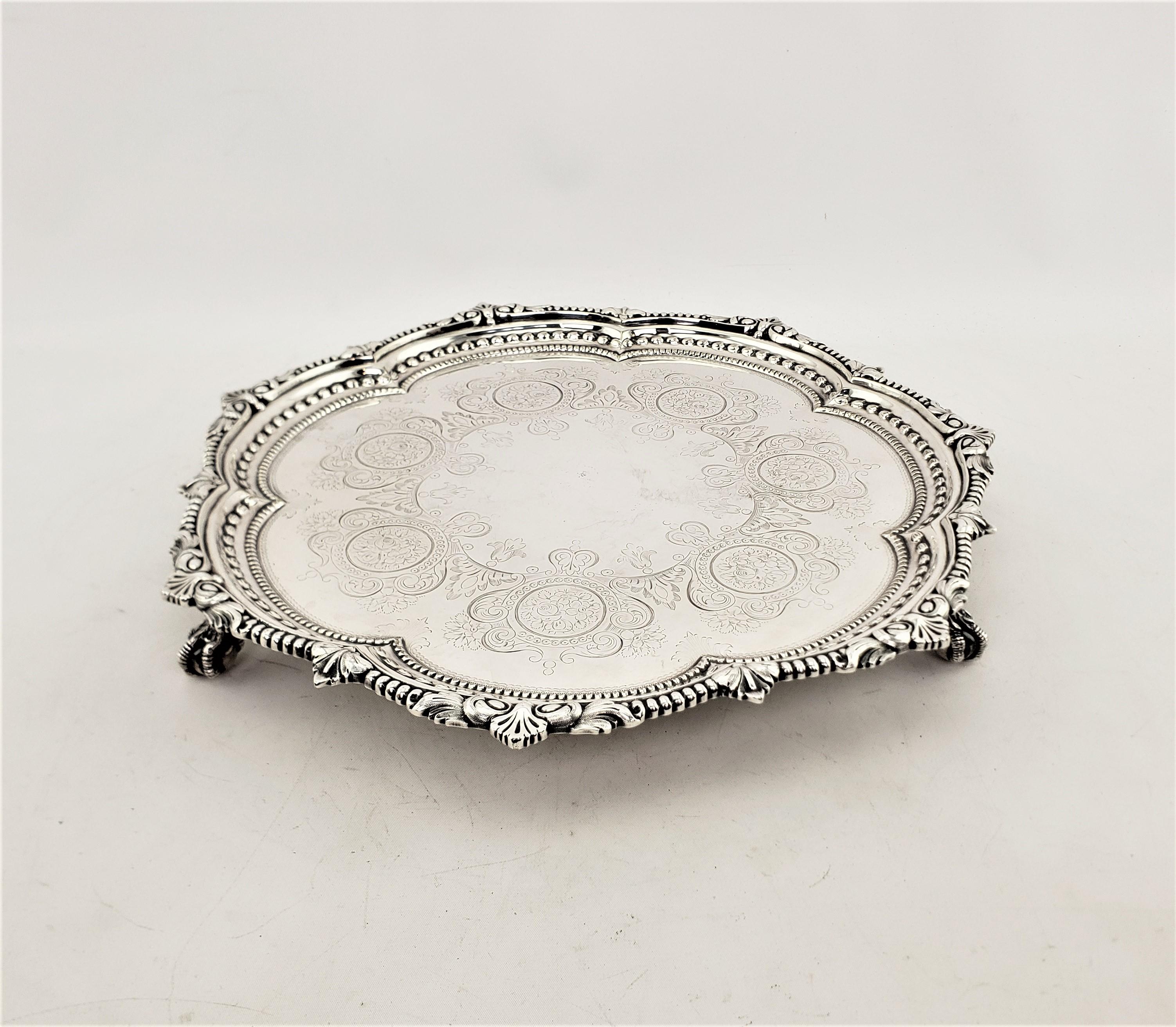 This antique silver plated serving tray is hallmarked by an unknown maker, and presumed to have originated from England and date to approximately 1920 and done in a Victorian style. This silver plated serving tray is scalloped shaped with layers of