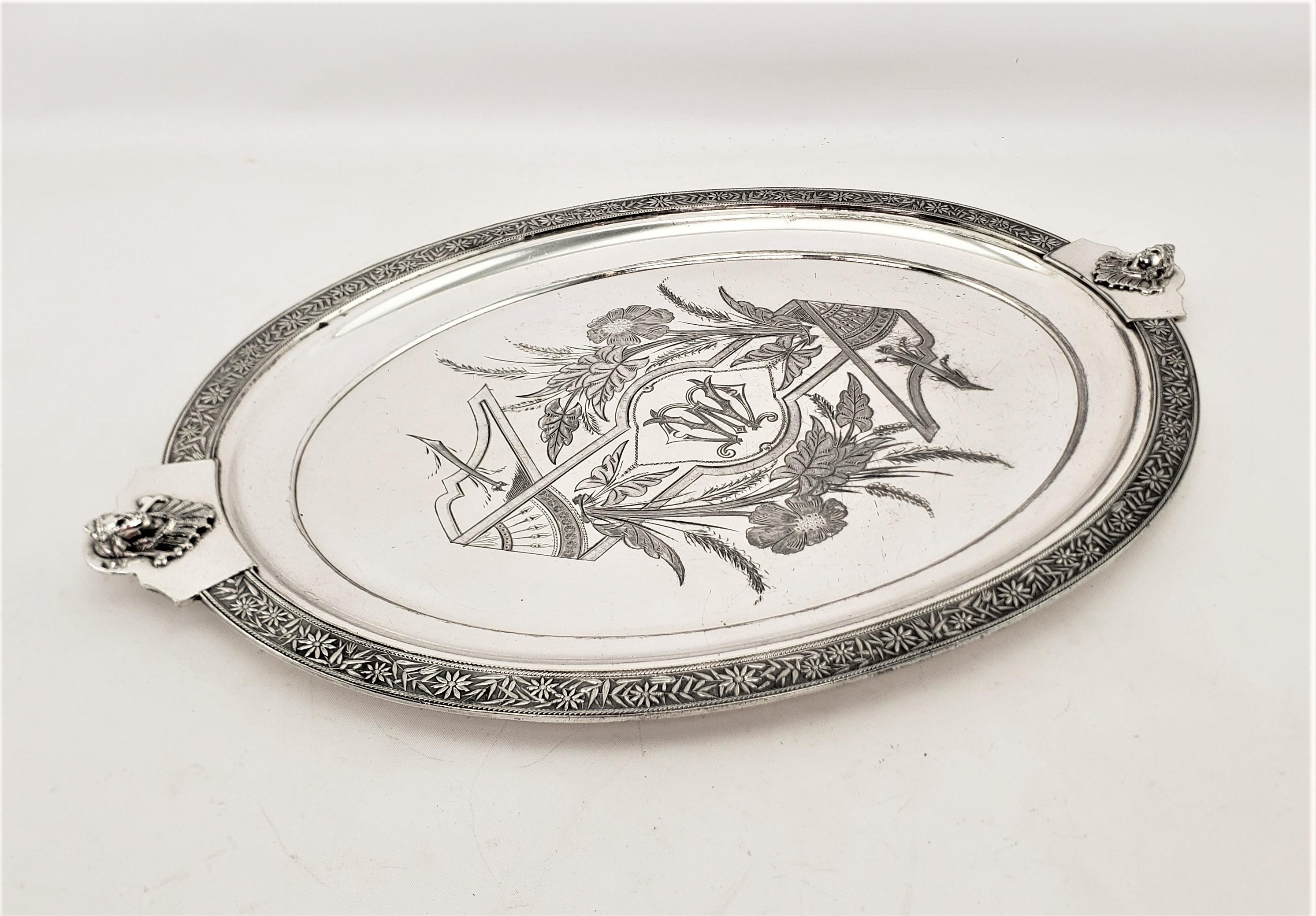 This antique oval silver plated serving tray was made by the Merdian Silver Plate Co. of England in approximately 1920 and done in a Neoclassical Revival style. The tray has bold engraving on the top surface with a monogram in the center, surrounded