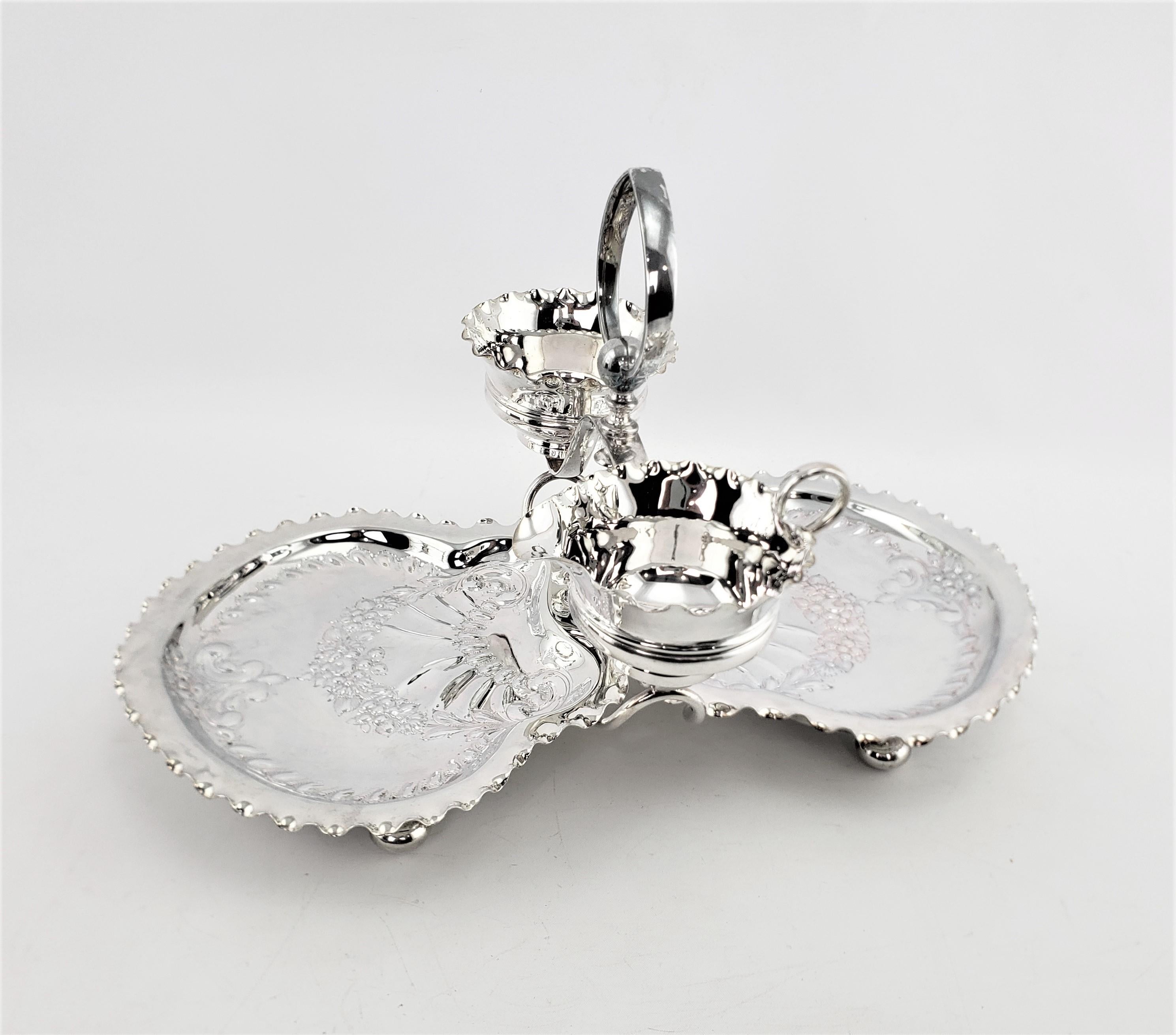 This antique silver plated berry server is signed by an unknown maker, but believed to originate from England and date to approximately 1920 and done in a slightly earlier Edwardian style. The set is composed of a rack or stand with bun feet, two