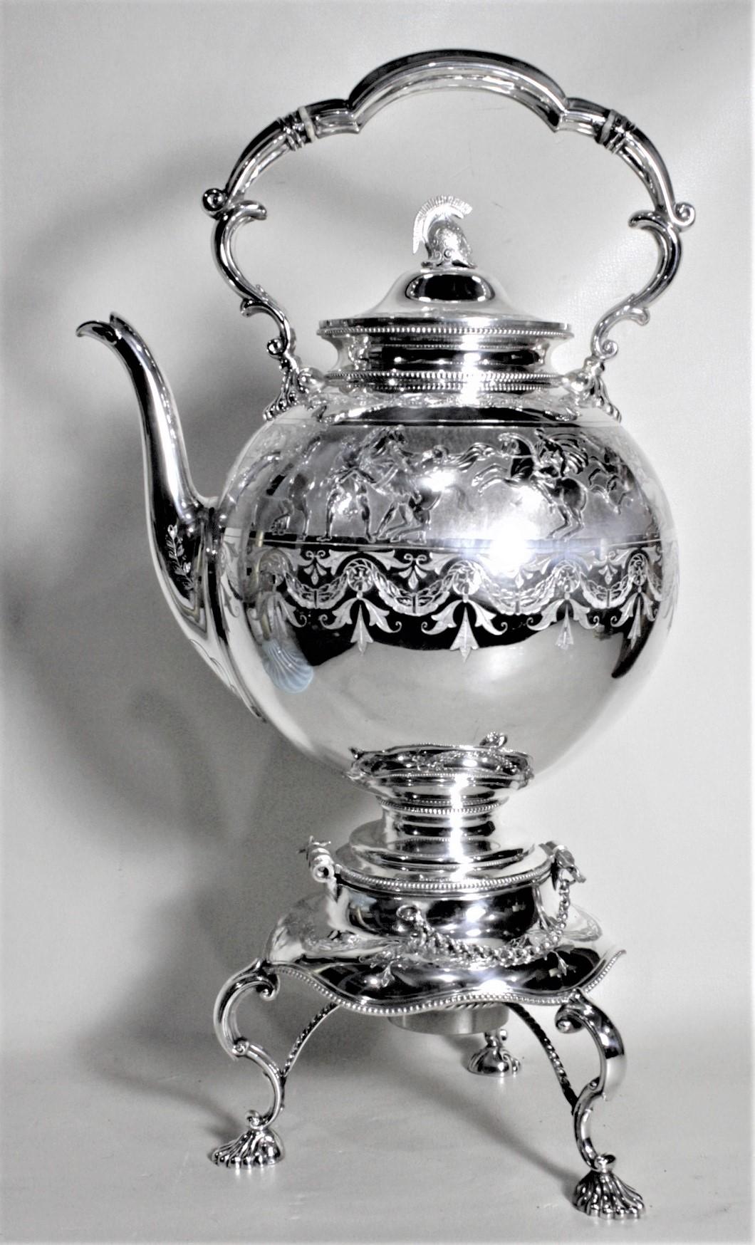 This antique silver plated tipping kettle or teapot originates from England and dating from circa 1900 and done in the period Edwardian style. The teapot or kettle has an interesting figural helmet finial on the top and heavily engraved sides done