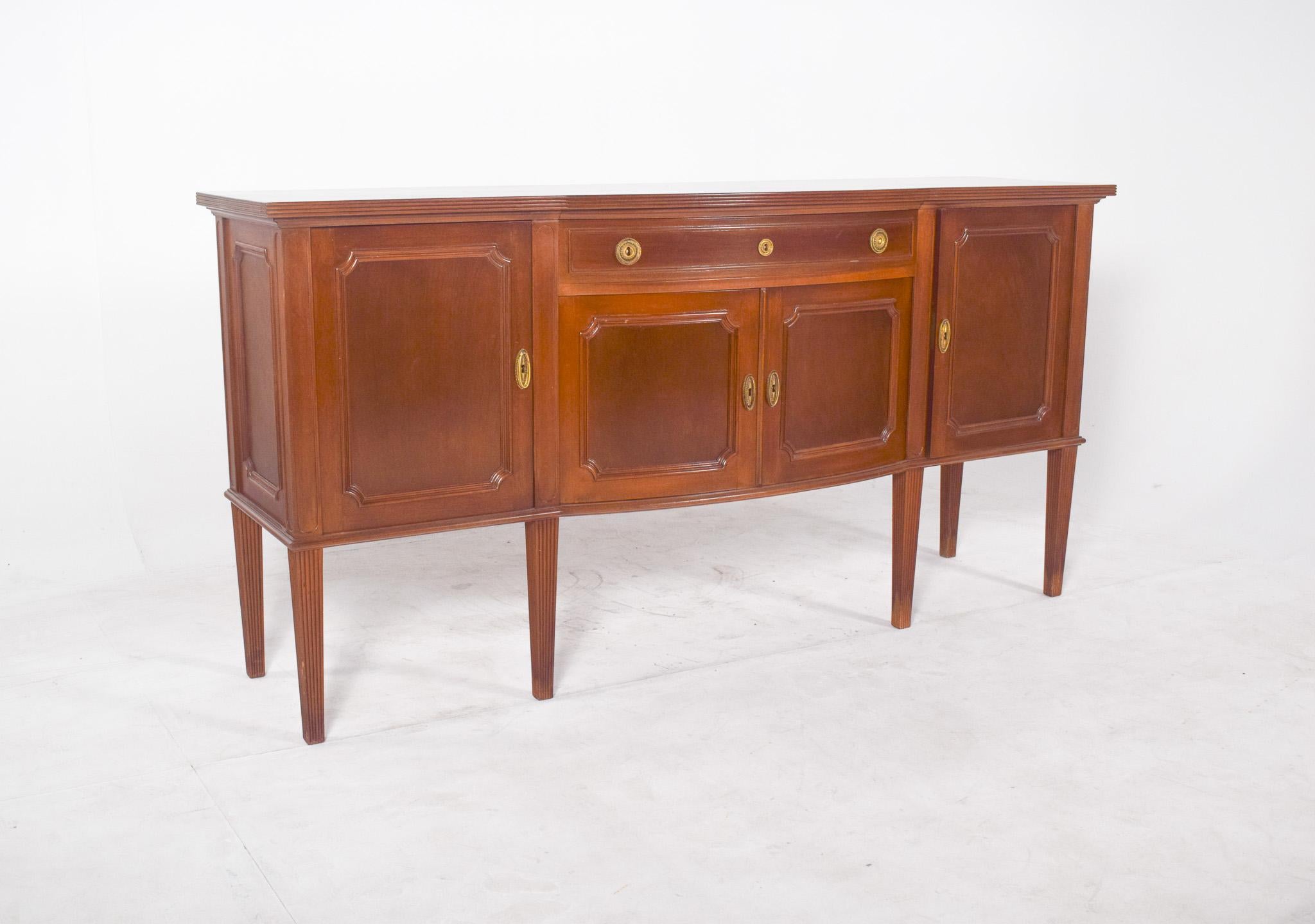 Six-legged sideboard. Its straight structure is gently broken by the slight central curvature of the double doors, which give the piece movement and delicacy. The framed panels on the four doors, the oval inlaid handle and the gold appliqués on the