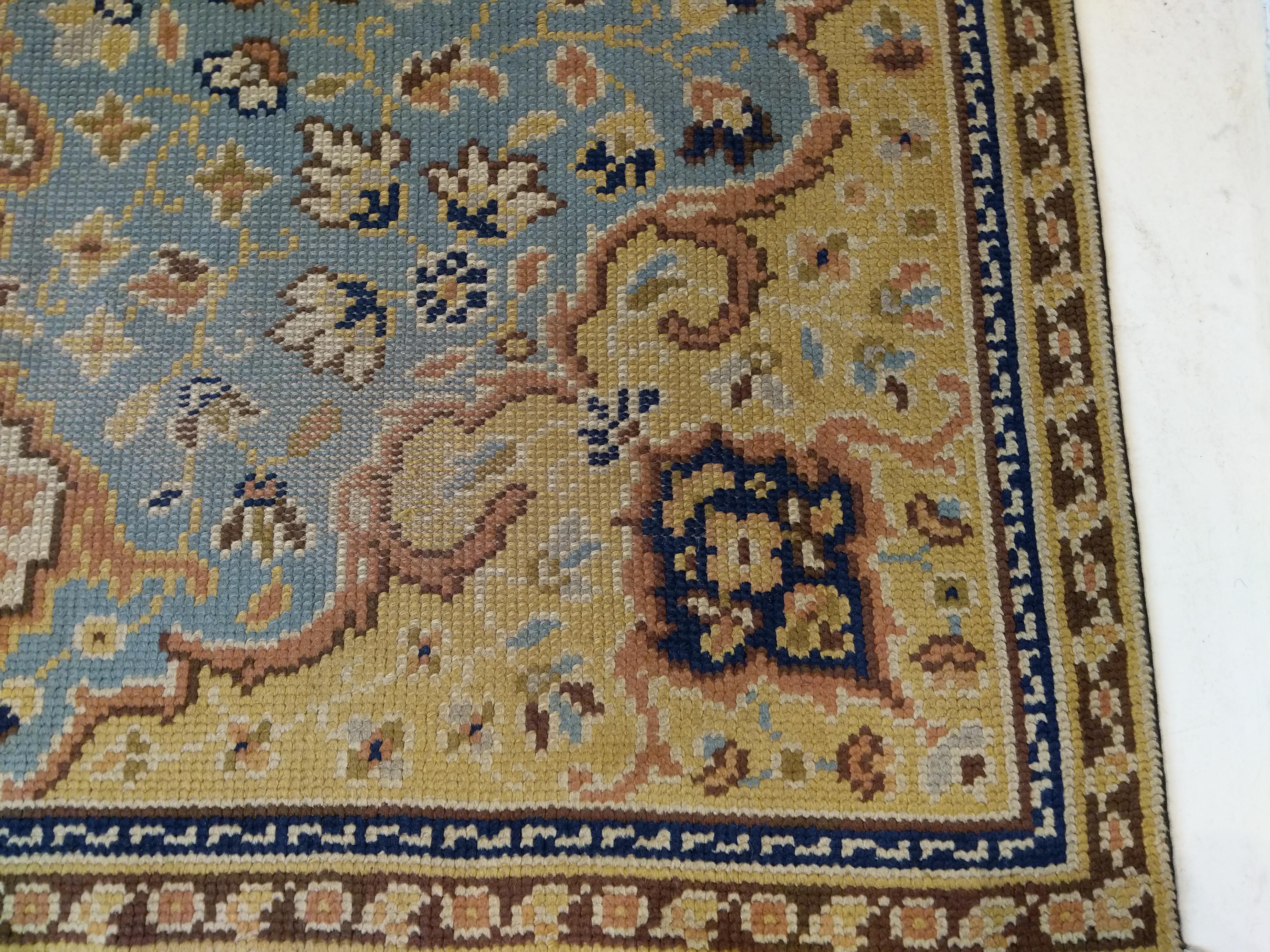 Dieser Teppich, der eindeutig von der Mode der Orientteppiche inspiriert ist, die zu Beginn des 20. Jahrhunderts ihren Höhepunkt erreichte, zeichnet sich durch ein vielschichtiges Medaillon- und Anhänger-Muster aus, das auf einem himmelblauen