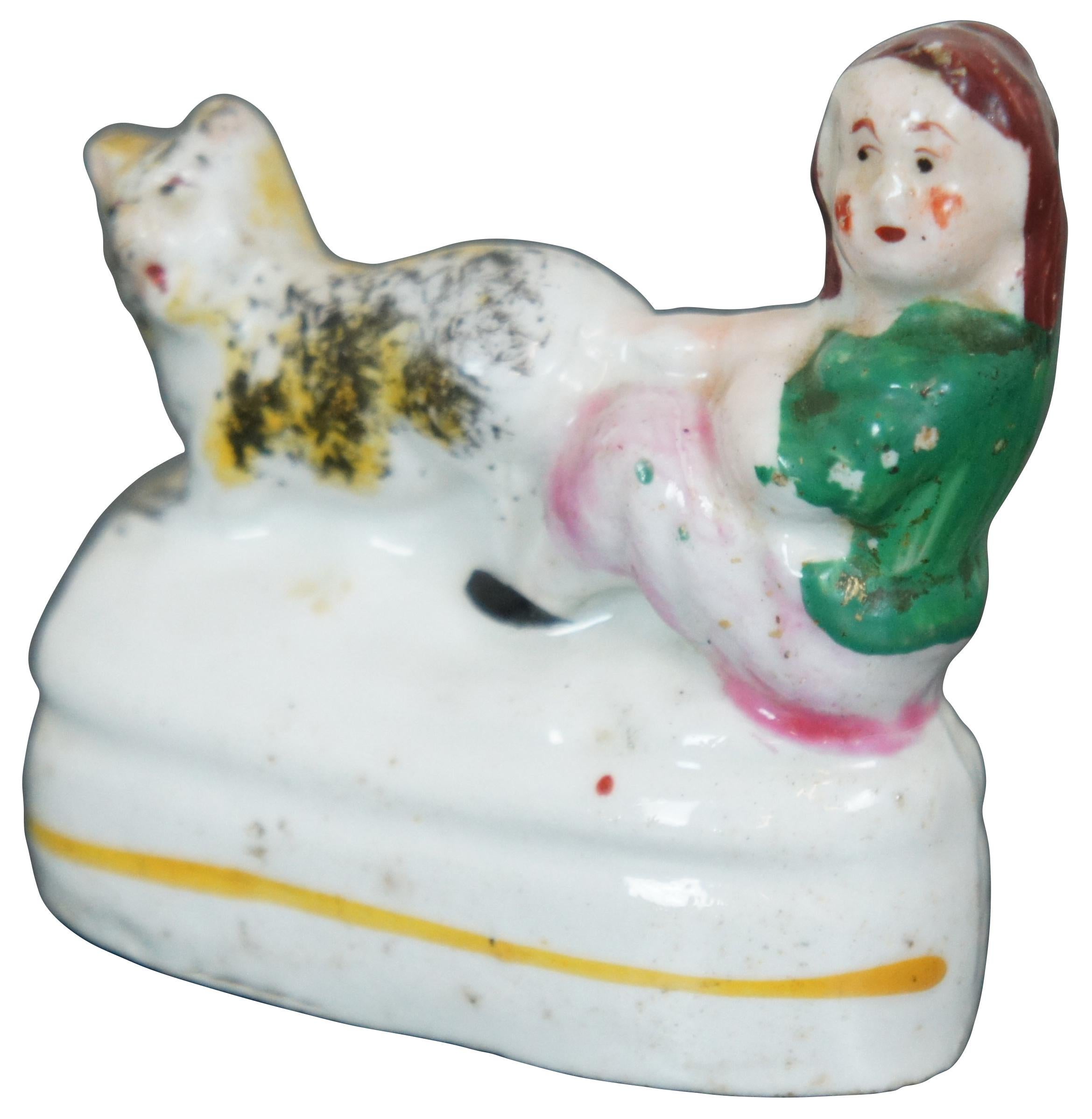 Antique 19th century miniature porcelain figurine in the shape of a child pulling a cat’s tail.