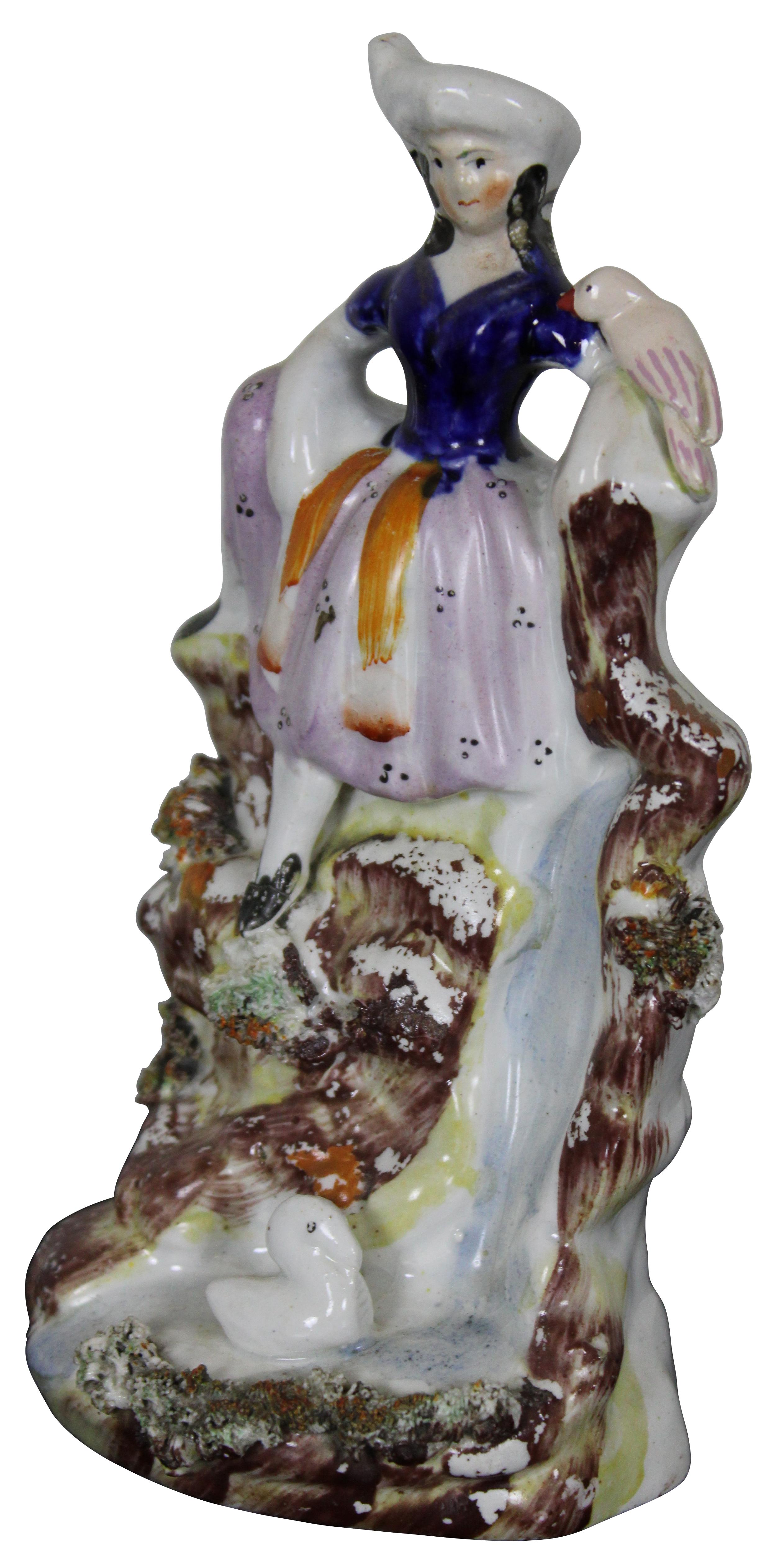 Antique 19th century staffordshire porcelain figure showing a young woman seated on the rocks above a waterfall with two birds.