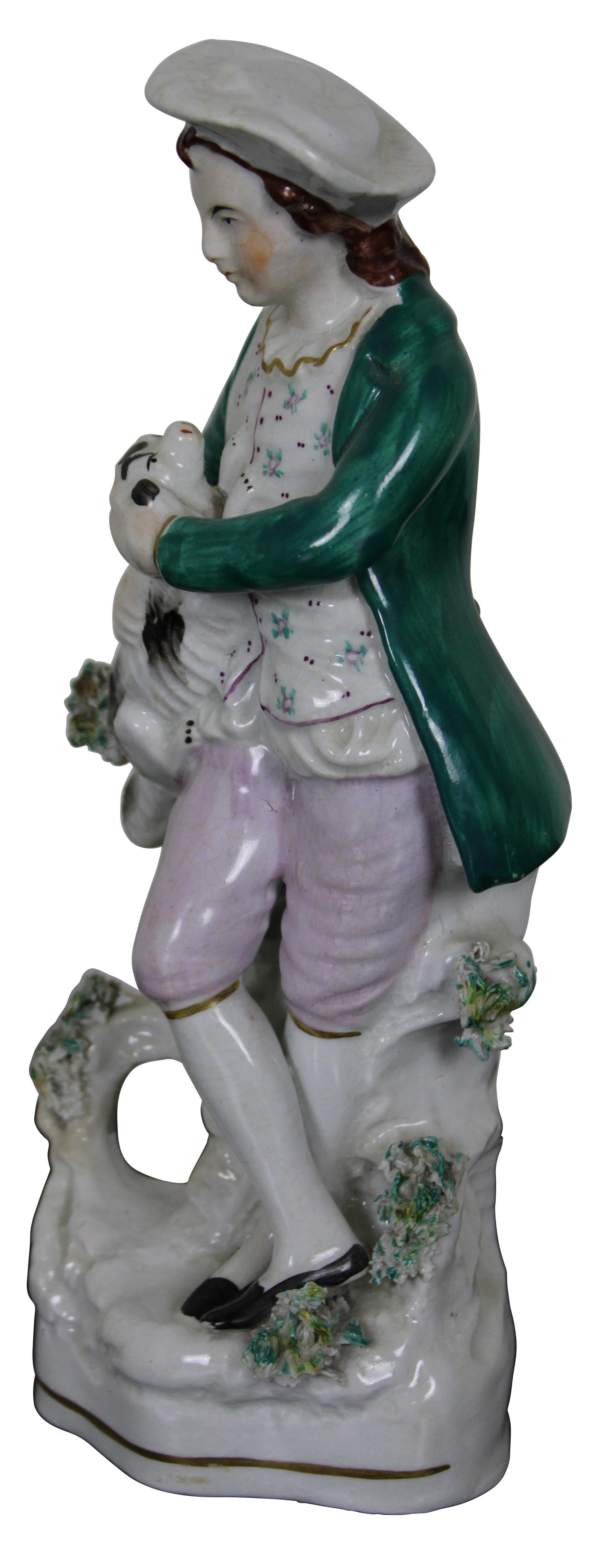 Antique Victorian Staffordshire porcelain figurine in the shape of a man holding a small spotted Spaniel dog. Measure: 8
