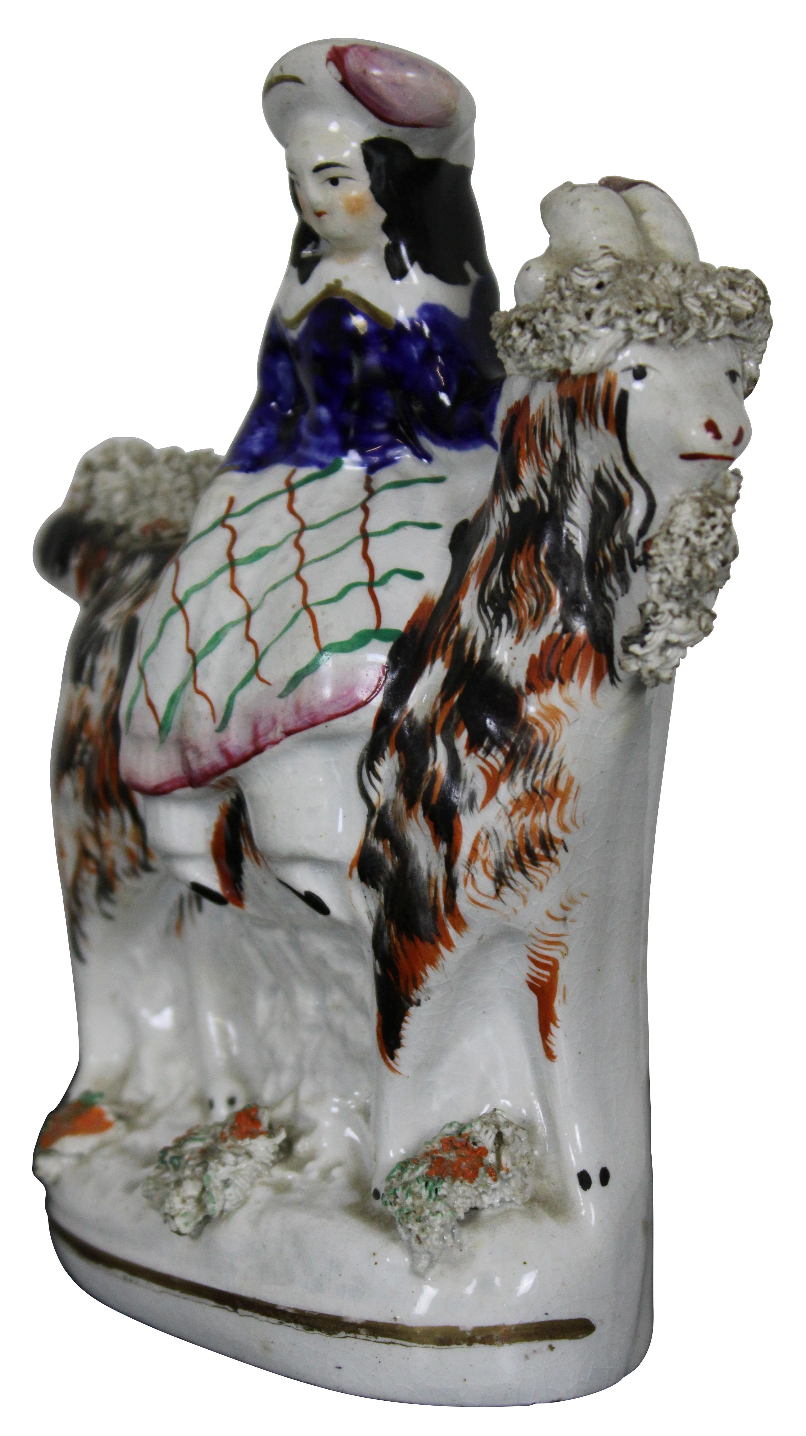 Antique 19th century Staffordshire England porcelain figurine of a Scottish girl dressed in traditional attire with plaid skirt; seated on a large shaggy goat. Measures: 5.5