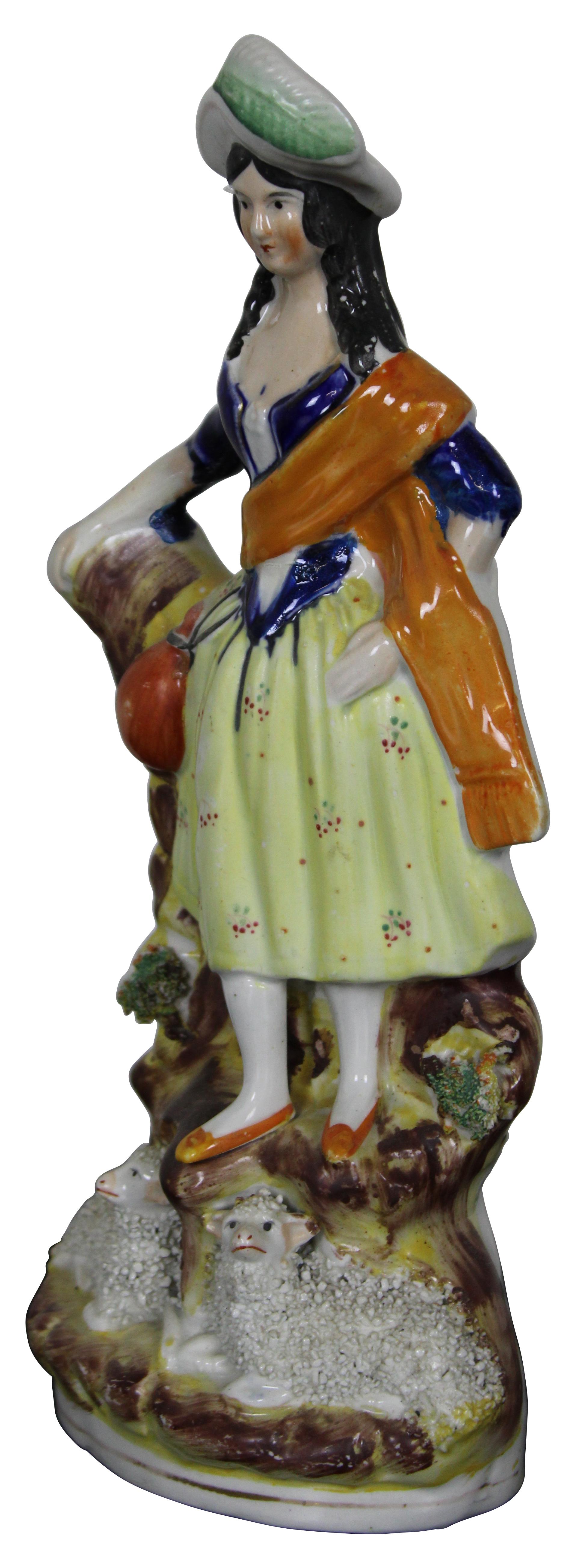 Antique 19th century English Staffordshire porcelain figurine in the shape of a Scottish woman standing by a tree stump, watching over a pair of textured sheep / lambs. 
     