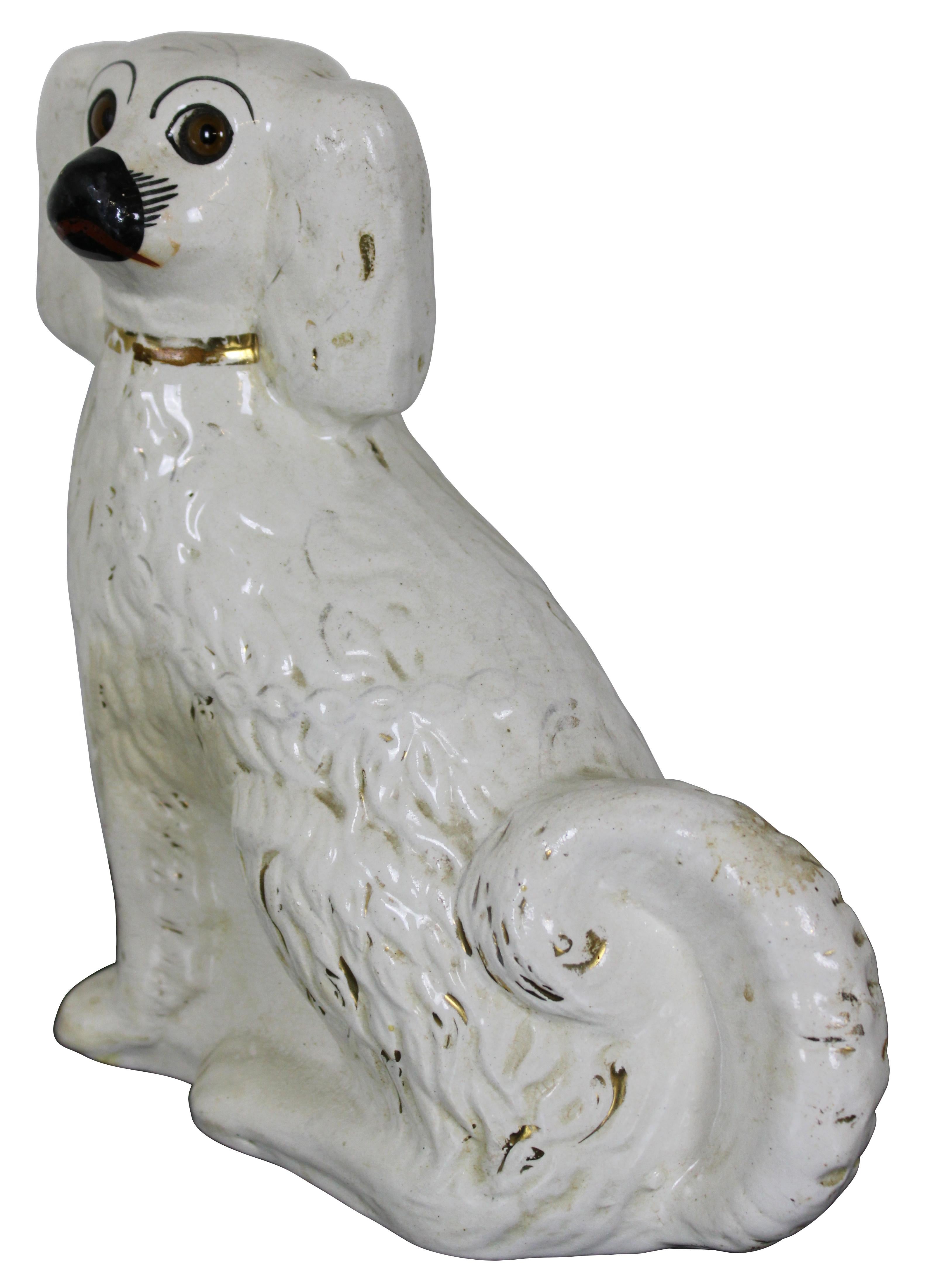 Antique Staffordshire porcelain figurine in the shape of a King Charles Spaniel with golden collar and brown glass eyes. Measure: 9