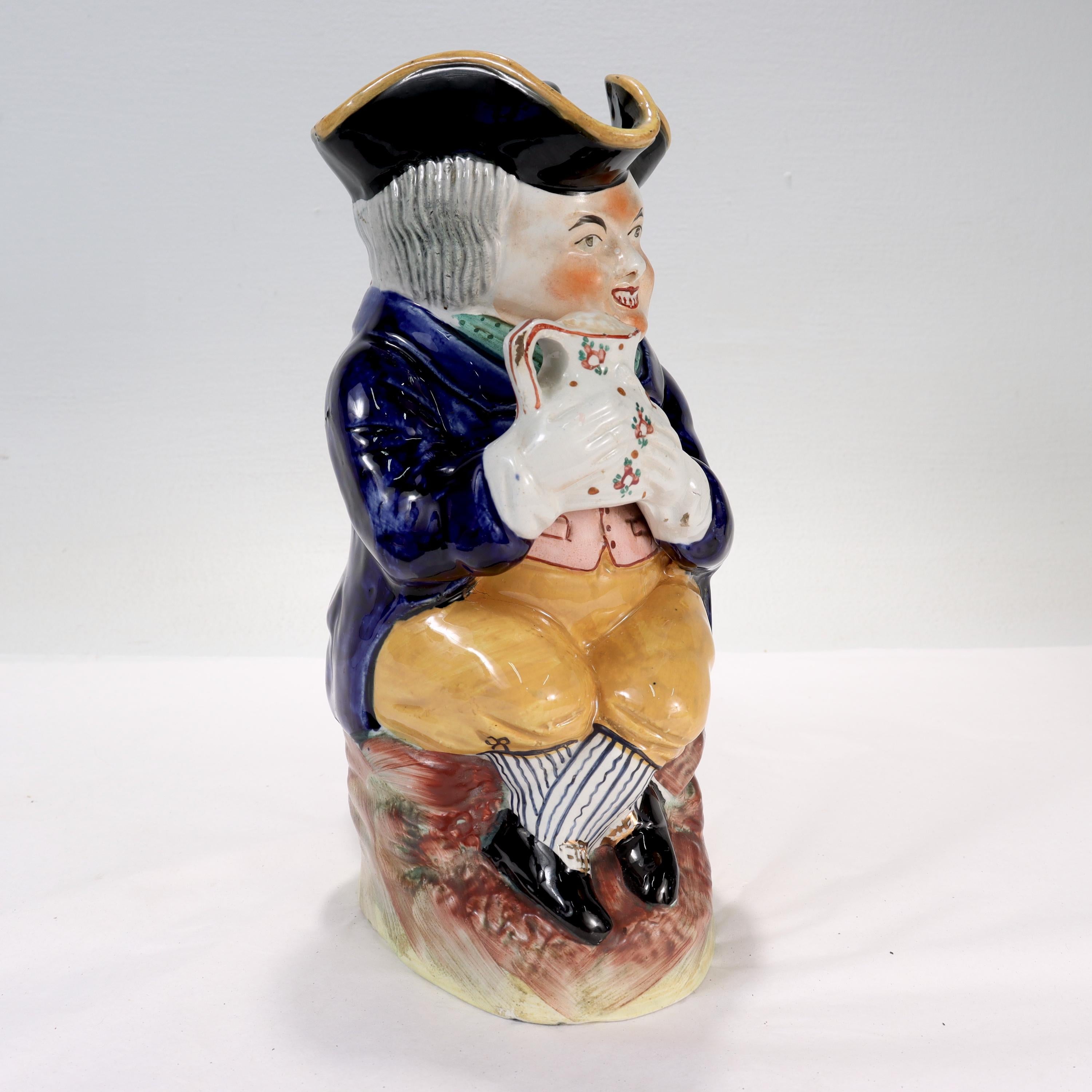 A fine antique Staffordshire pottery Toby Jug.

In the form of a seated, smiling man holding a jug.

The man's tricorn hat serves as a lid, and an integral handle runs down his back.

Simply a great Toby Jug!

Date:
19th Century

Overall