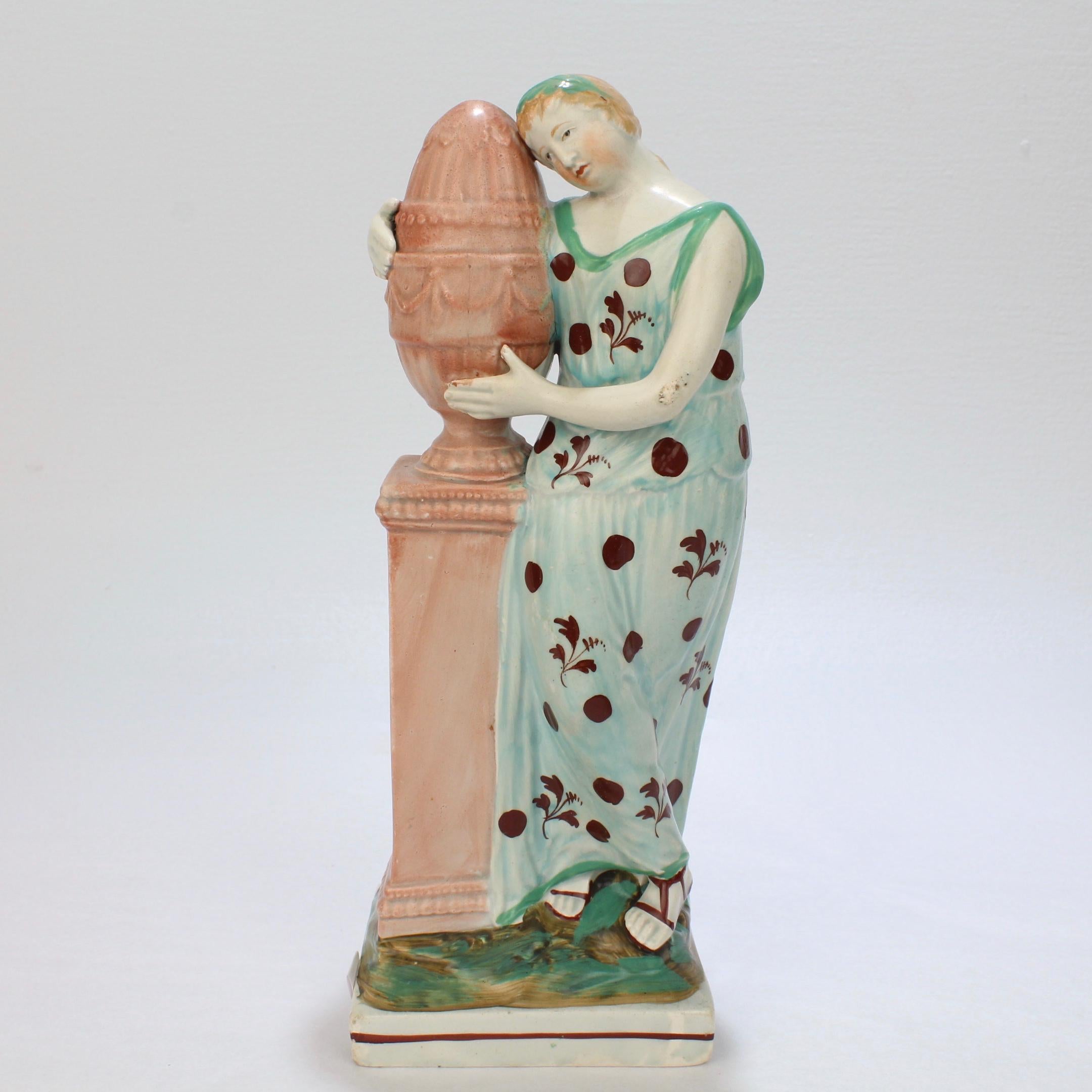 Une belle figurine ancienne en faïence. 

Représentation d'Andromaque étreignant (et pleurant) l'urne d'Hector soutenue par un socle. 

Décor polychrome. 

Il s'agit tout simplement d'une magnifique figure allégorique anglaise de la première heure