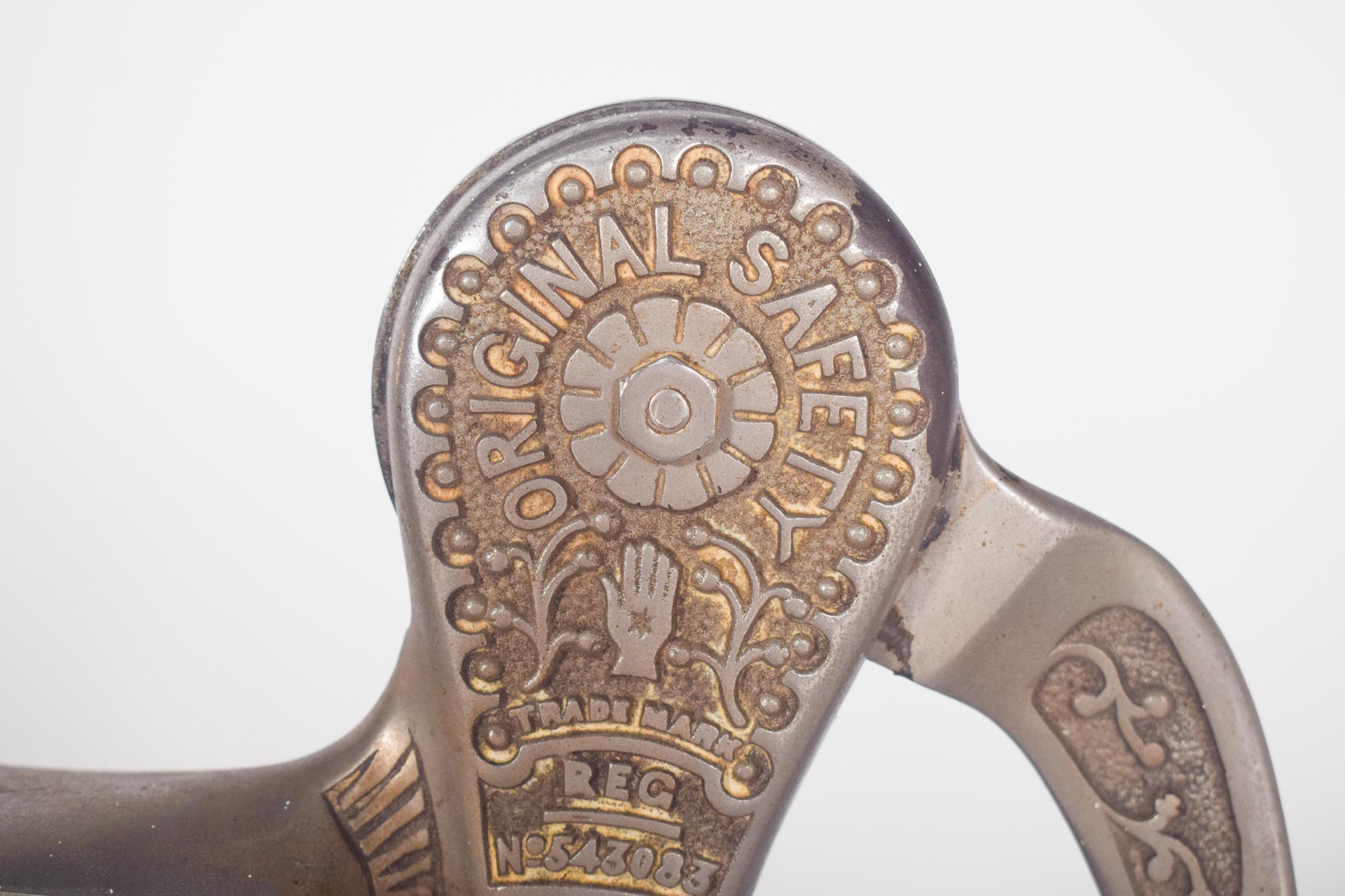 Steel bottle opener. Embossed decoration with floral motifs. The robust design and large lever indicate that it is designed to open bottles efficiently, possibly being fixed to a table or counter by means of a clamping system. The crank with a dark