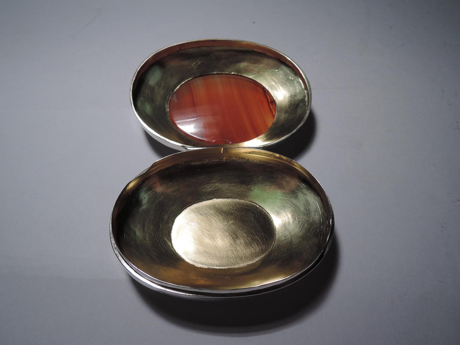 English Victorian sterling silver and agate box, 1876. Oval with canted shoulders. Cover hinged and inset with translucent red agate. Gilt interior. Fully marked including indistinct maker's mark and Birmingham assay stamp. Total weight: 2.4 troy
