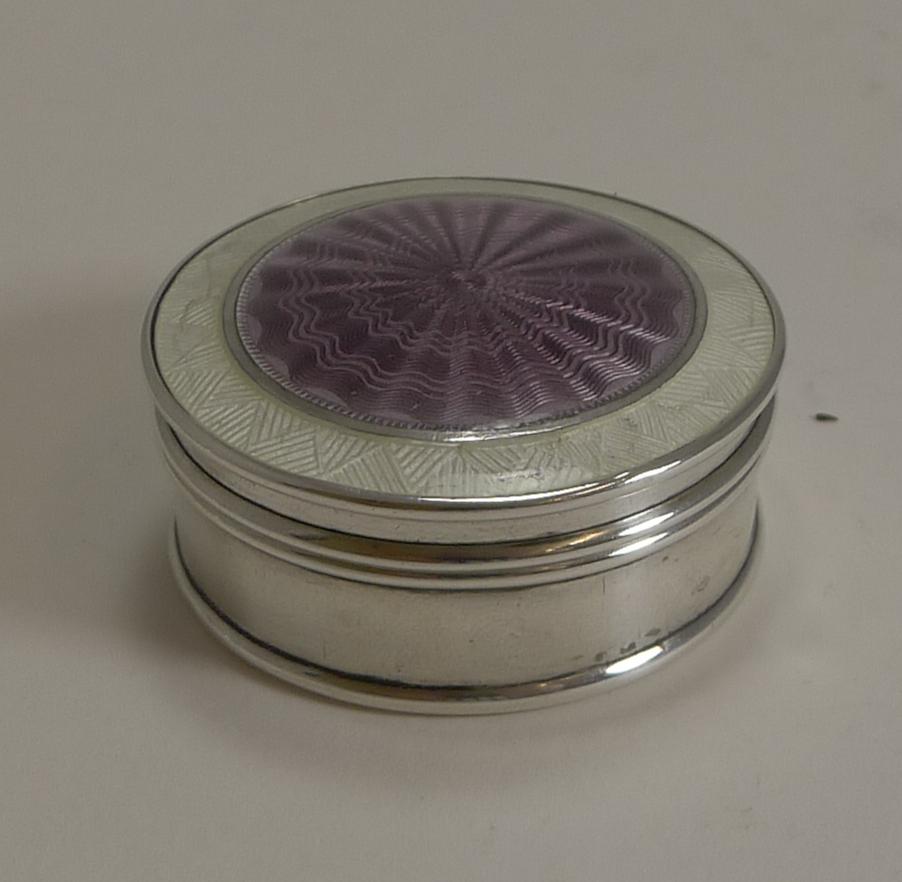 A fabulous antique silver pill box fully hallmarked for Birmingham 1911 together with the makers mark for the silversmith, Cohen & Charles.

The lift-off lid is beautifully decorated with a central Amethyst coloured panel of guilloche enamel