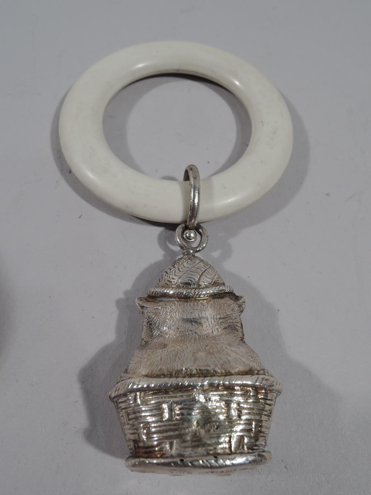 George V sterling silver baby rattle. Made by WH Collins & Co. in Birmingham in 1932. Flat and round ring with loose-mounted figural pendant: A cat in a basket with self-satisfied expression and fat paws. Nice jangly sound. Fully marked.