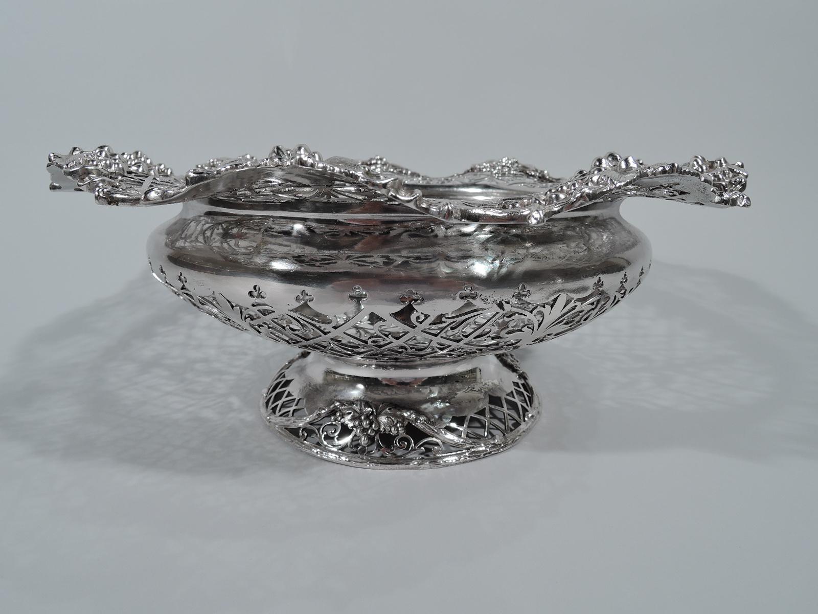 George V sterling silver bowl. Made by James Dixon & Sons in Sheffield in 1911. Bellied with domed foot. Solid multi-foil well and pierced trellis with stylized foliage. Wavy grapevine rim with applied bunches. Foot same. Perfect for the fruit and