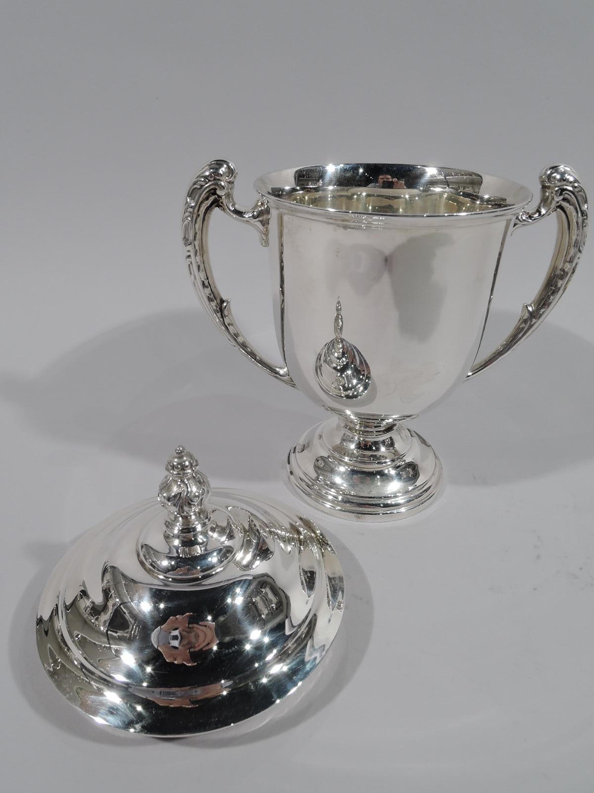 George V sterling silver trophy cup. Made by Elkington & Co. in Birmingham in 1912. Urn with opping leaf-capped side handles and stepped foot. Stepped domed cover with ornamental finial. Traditional amphora form in small scale. Fully marked and