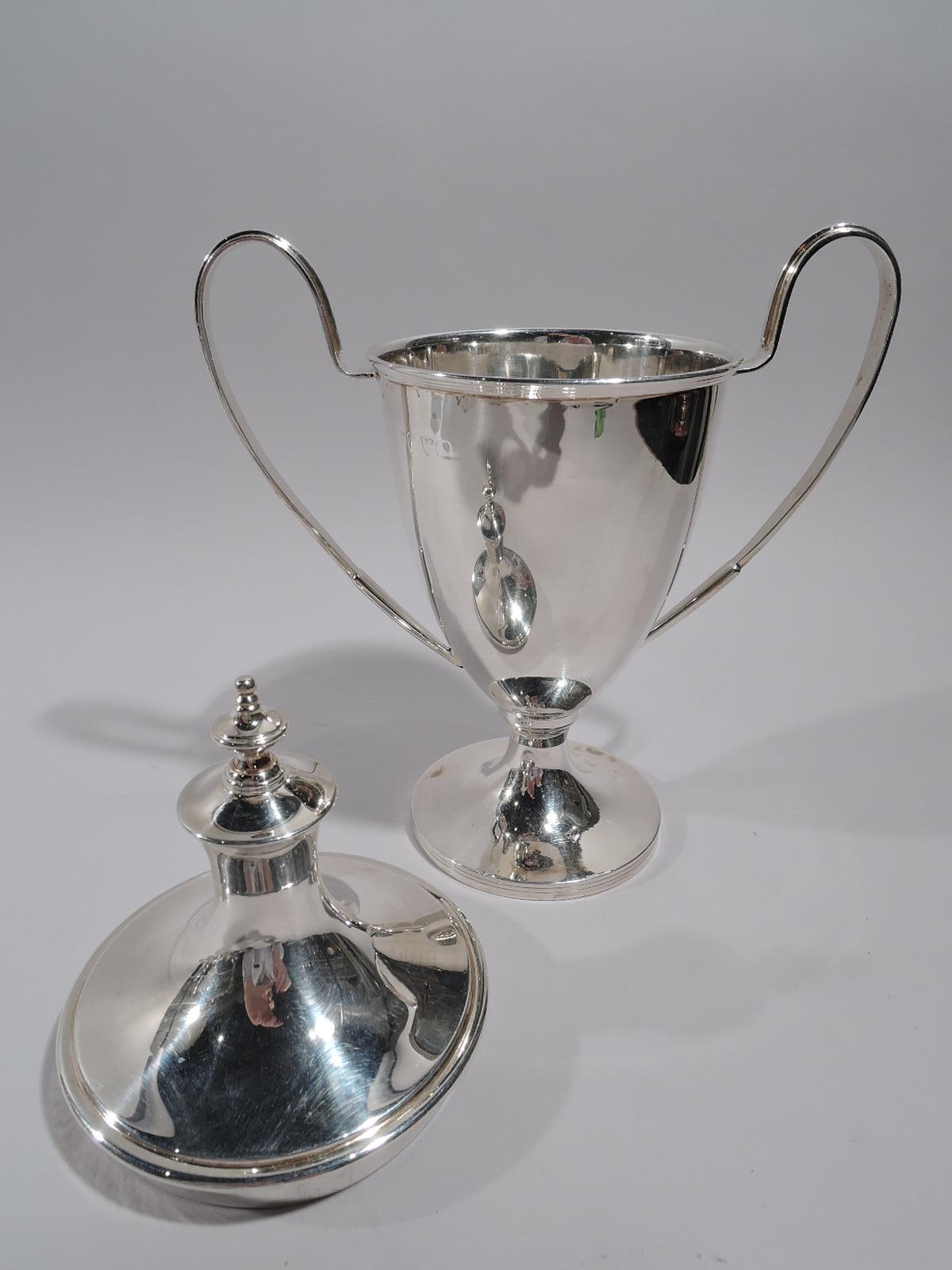 English sterling silver trophy cup, circa 1920. Urn with high-looping sides handles and raised foot. Cover domed with vase finial. Smallish. Traditional form. Fully marked including maker (Barker Bros) and assay (Chester) stamps, and worn date