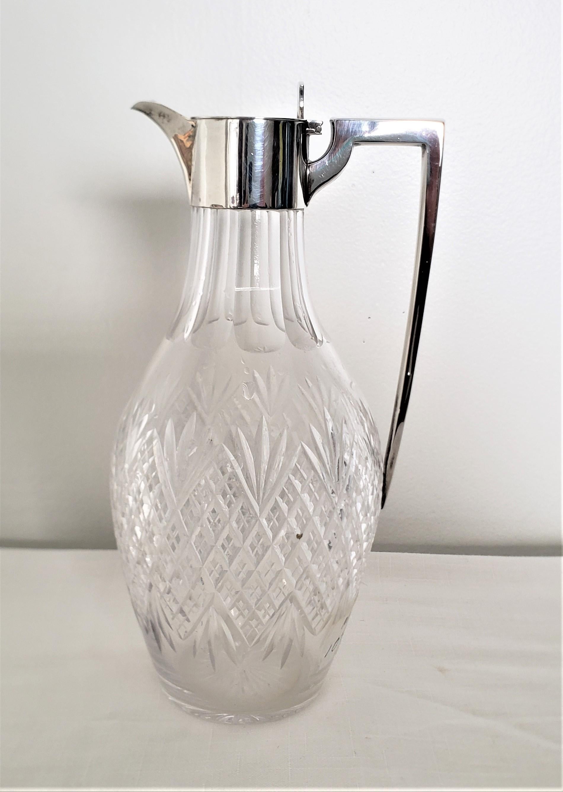 This antique cut glass and sterling silver claret jug is hallmarked by an unknown maker, but clearly originated from England and dates to approximately 1900 and done in the period Edwardian style. The top, neck and handle are done in sterling silver