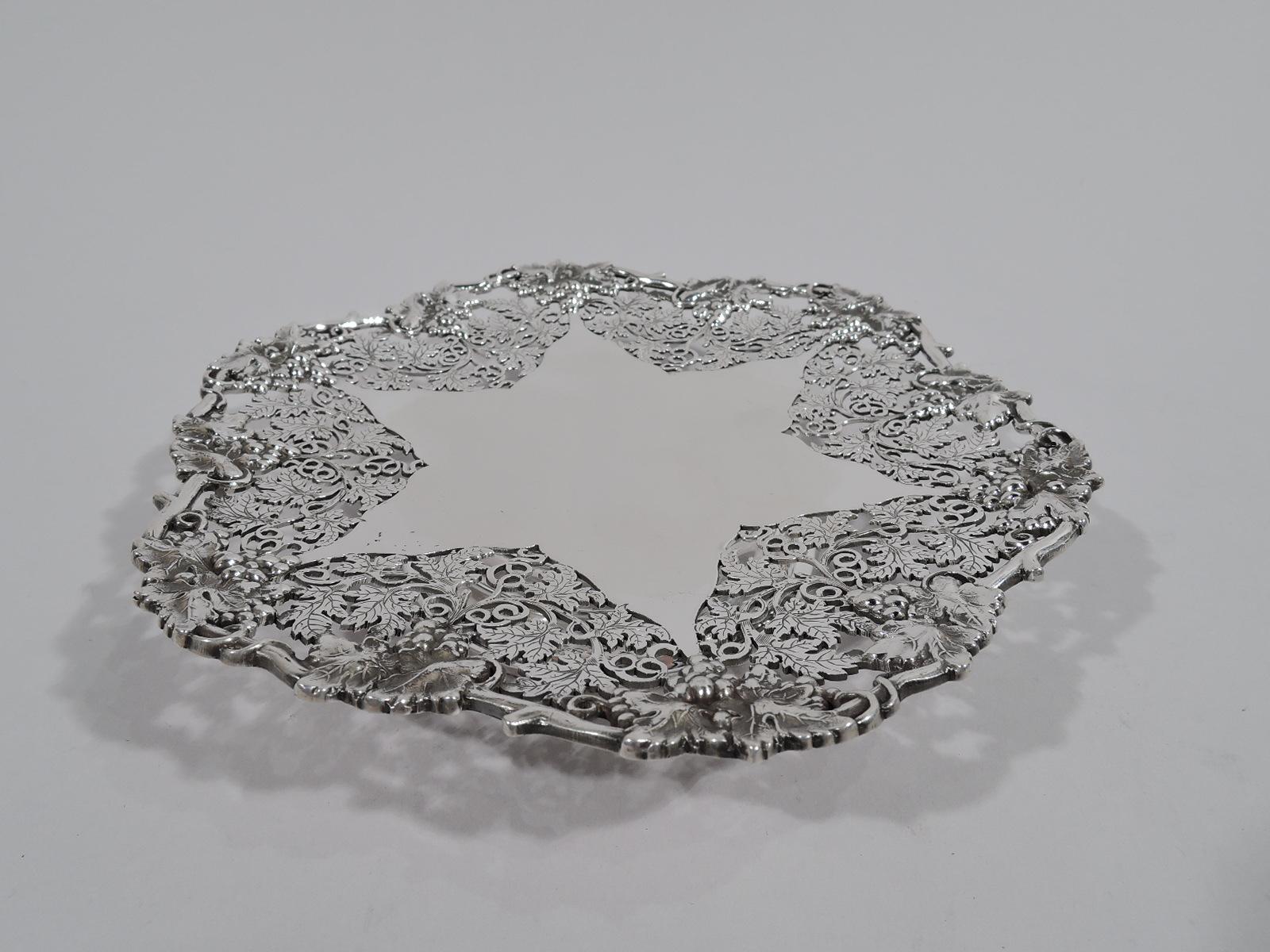 George V sterling silver footed plate. Made by Atkin Brothers in Sheffield in 1931. Round with solid irregular star surrounded by open leafing scrolls Applied wavy rim in form of fruiting grapevine. Foot is round and stepped. Fully marked. Heavy