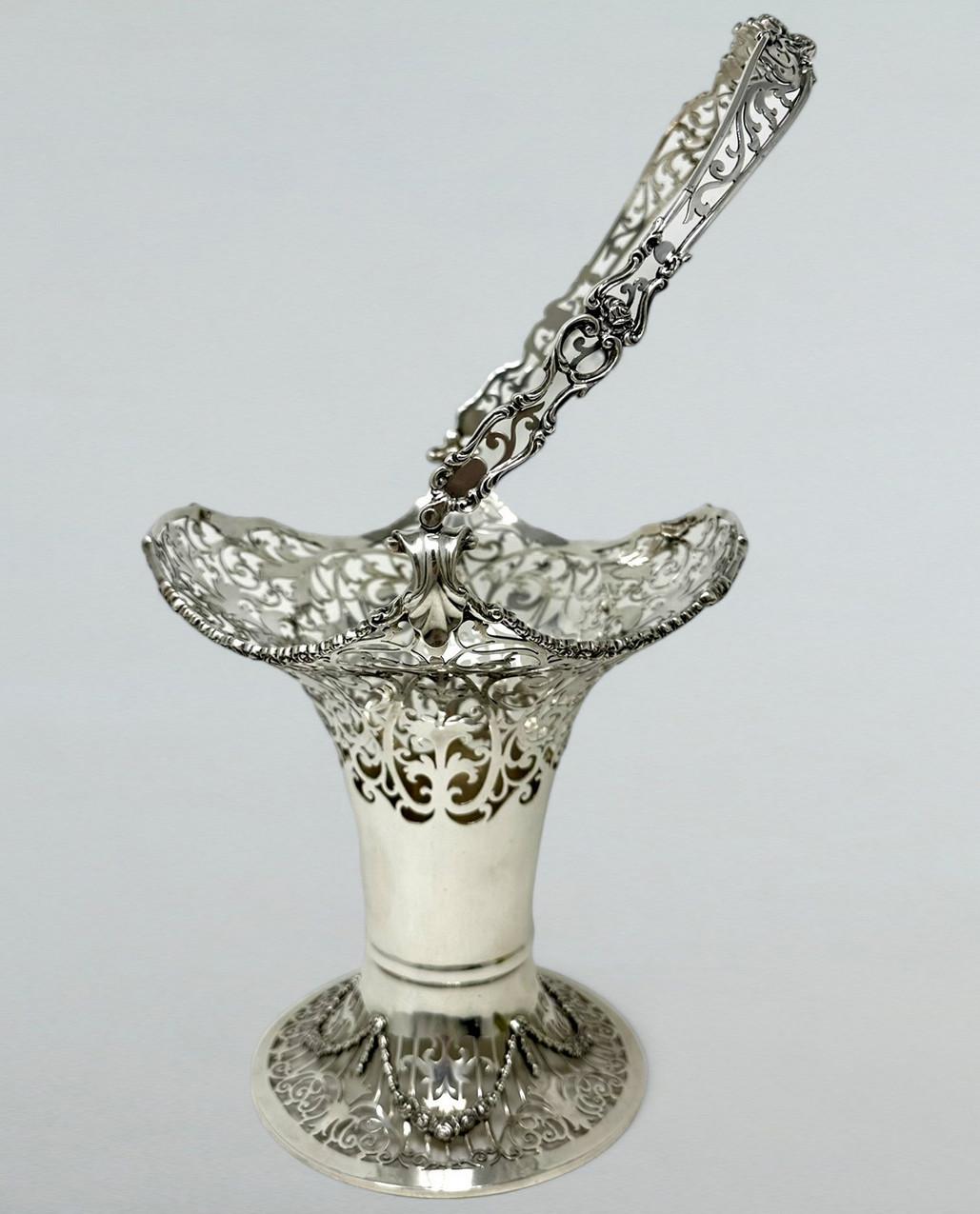 Superb Edwardian Heavy Gauge Silver Swing Handle Fruit Basket or Centerpiece of unusually large proportions and generous weight. 

The waisted form upper flaired body with lavish open fret work decoration, a central ring turned plain socle, ending