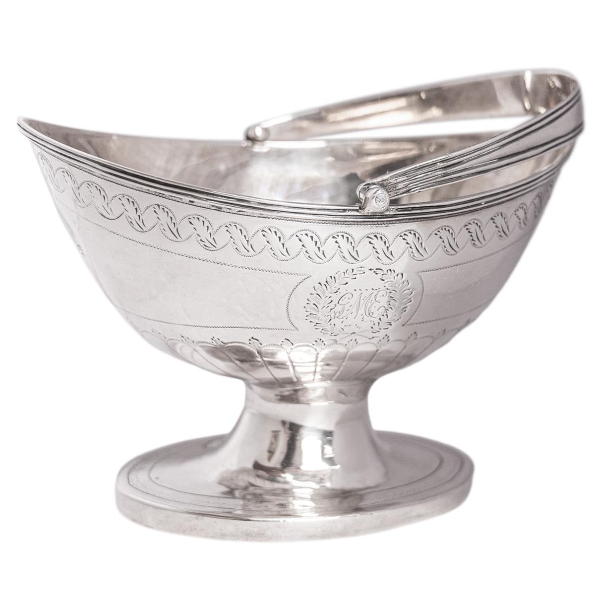 A fine antique Georgian sterling silver engraved sugar basket/bowl, London, circa 1790.
The sugar basket of helmet shape & fitted with a swing handle, the basket is rasied on a flared oval foot. The sugar basket is finely engraved with rope-twist