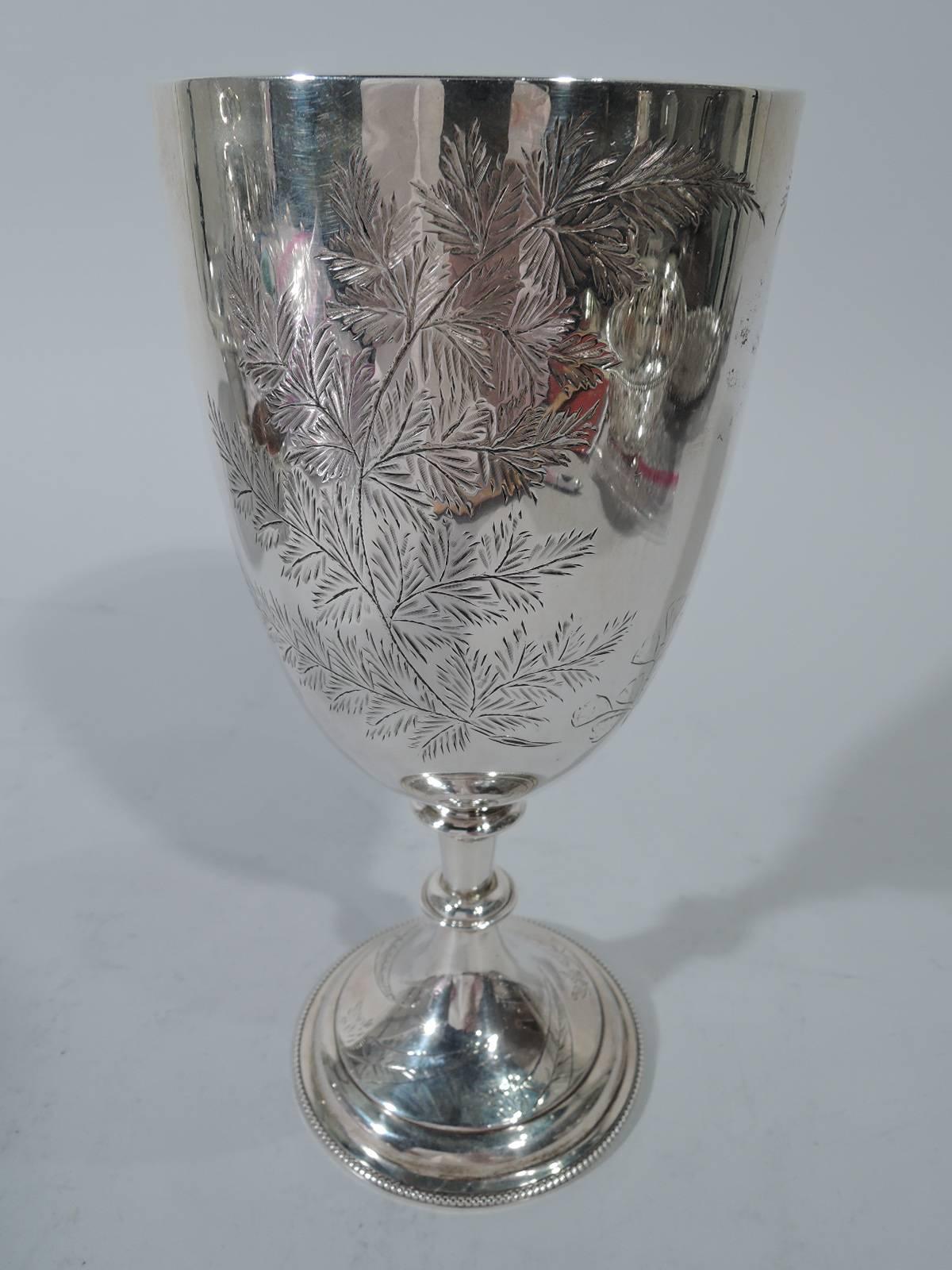 Victorian sterling silver goblet. Made by Charles Boyton in London in 1881. Large tapering bowl, knopped stem, and stepped dome foot. Leafy branches engraved on bowl, with two forming ovoid frame (vacant). Stylized leaves on foot. Beading applied to