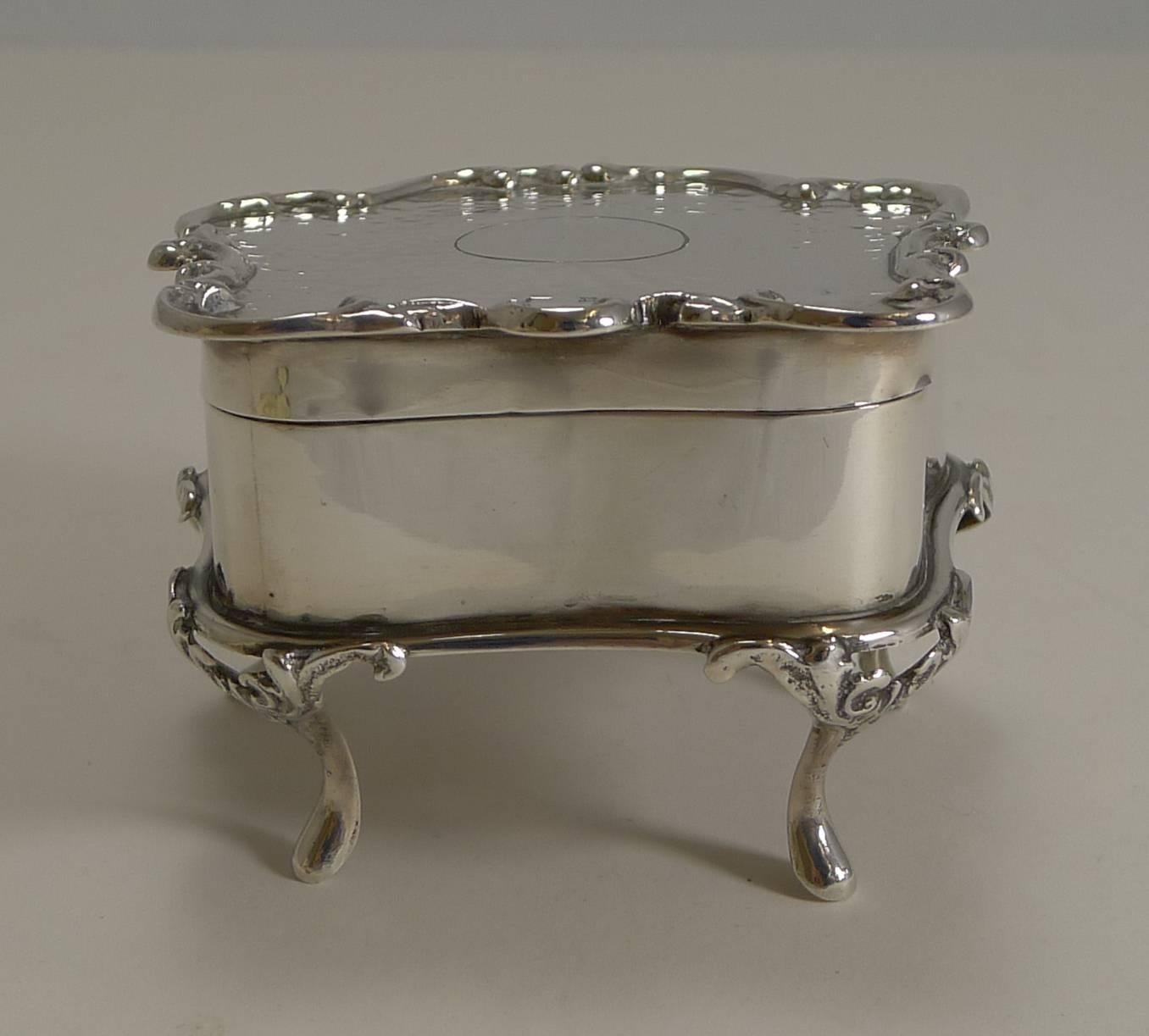 A handsome Edwardian jewelry or trinket co beautifully shaped and standing on four decorative cabriole legs. The lid is framed by a raised border with a hand planished decoration with a vacant circular cartouche to the centre.

The hinged lid fits