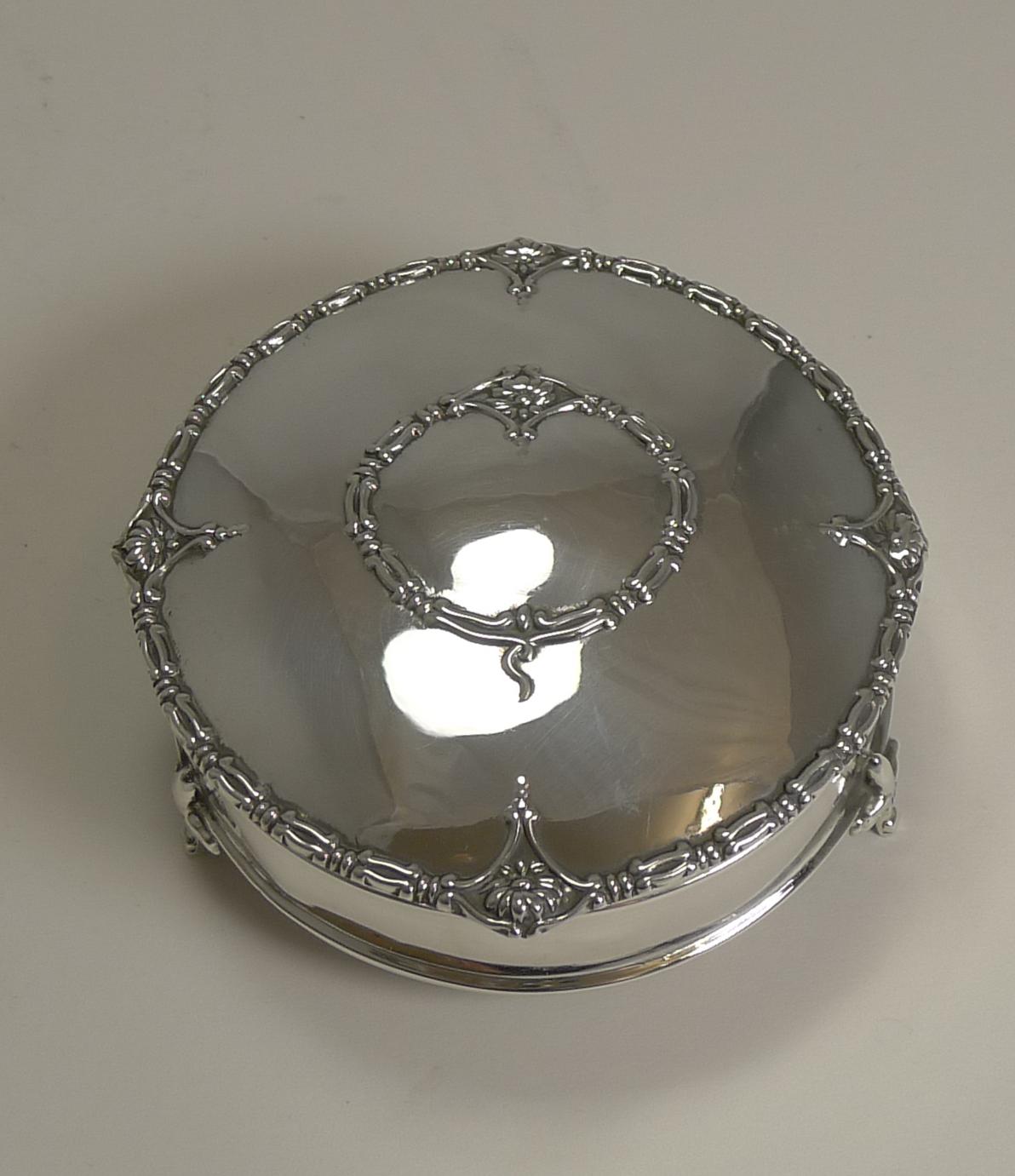 A beautifully decorated sterling silver jewellery or ring box standing on three elegant Fleur-de-Lys legs.

The lid is pretty as a picture with a raised border and a centrally framed vacant cartouche. The silver is fully hallmarked for Birmingham