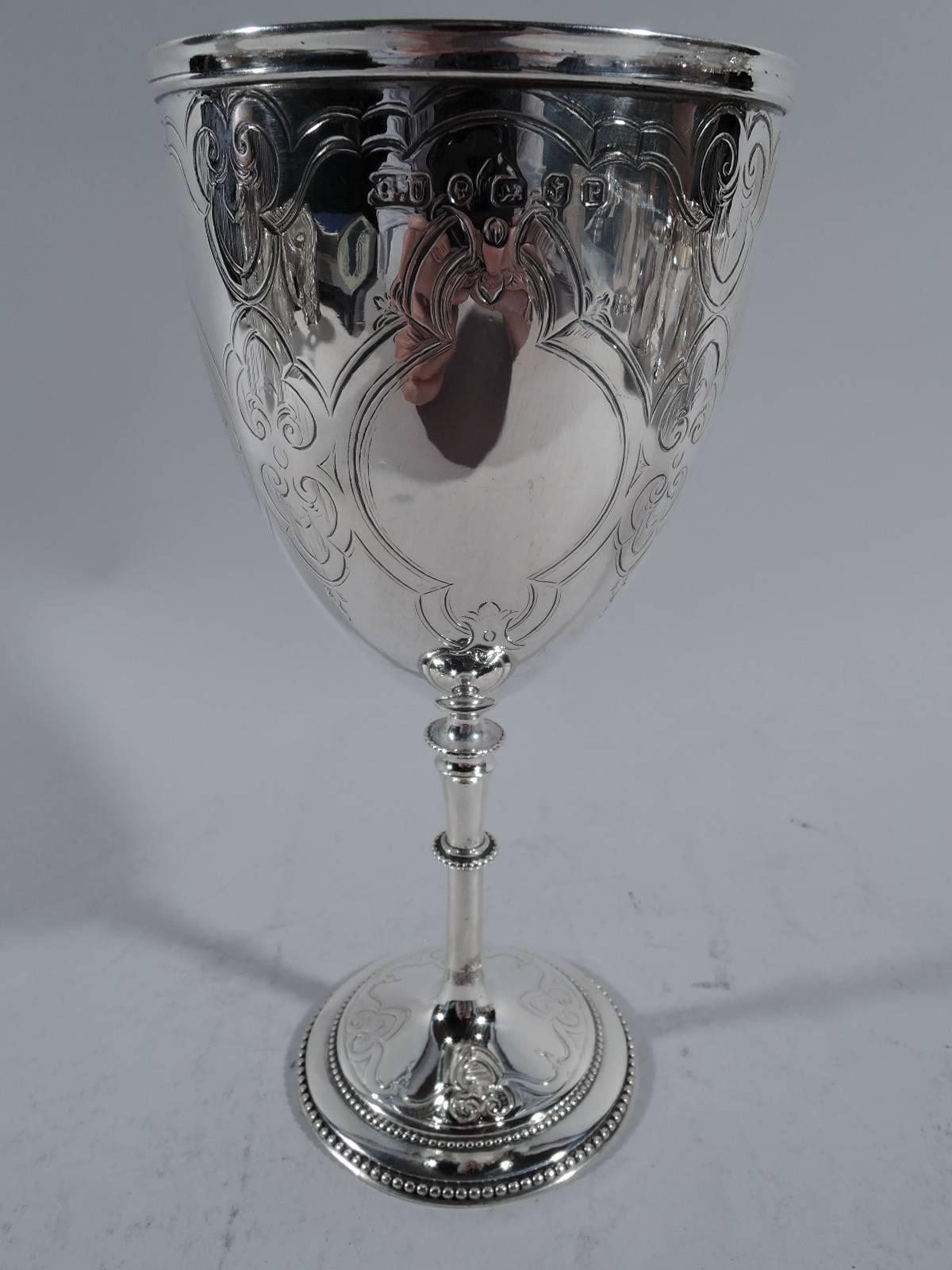 Victorian sterling silver goblet. Made by George Unite in Birmingham in 1864. Ovoid bowl with slender and knopped stem and stepped foot. Engraved ecclesiastical ornament: strapwork quatrefoils inset with crosses alternating with joined fleurs de