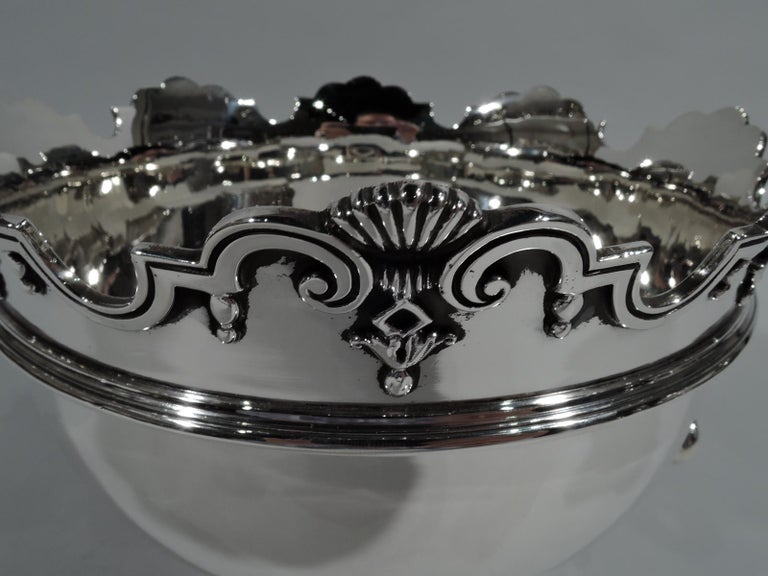 George V sterling silver monteith. Made by Samuel Walton Smith in London in 1912. Round and girdled bowl on stepped foot. Molded curvilinear rim with scallop shells and applied pendant flowers. Shaped and open side handles loose-mounted to winged