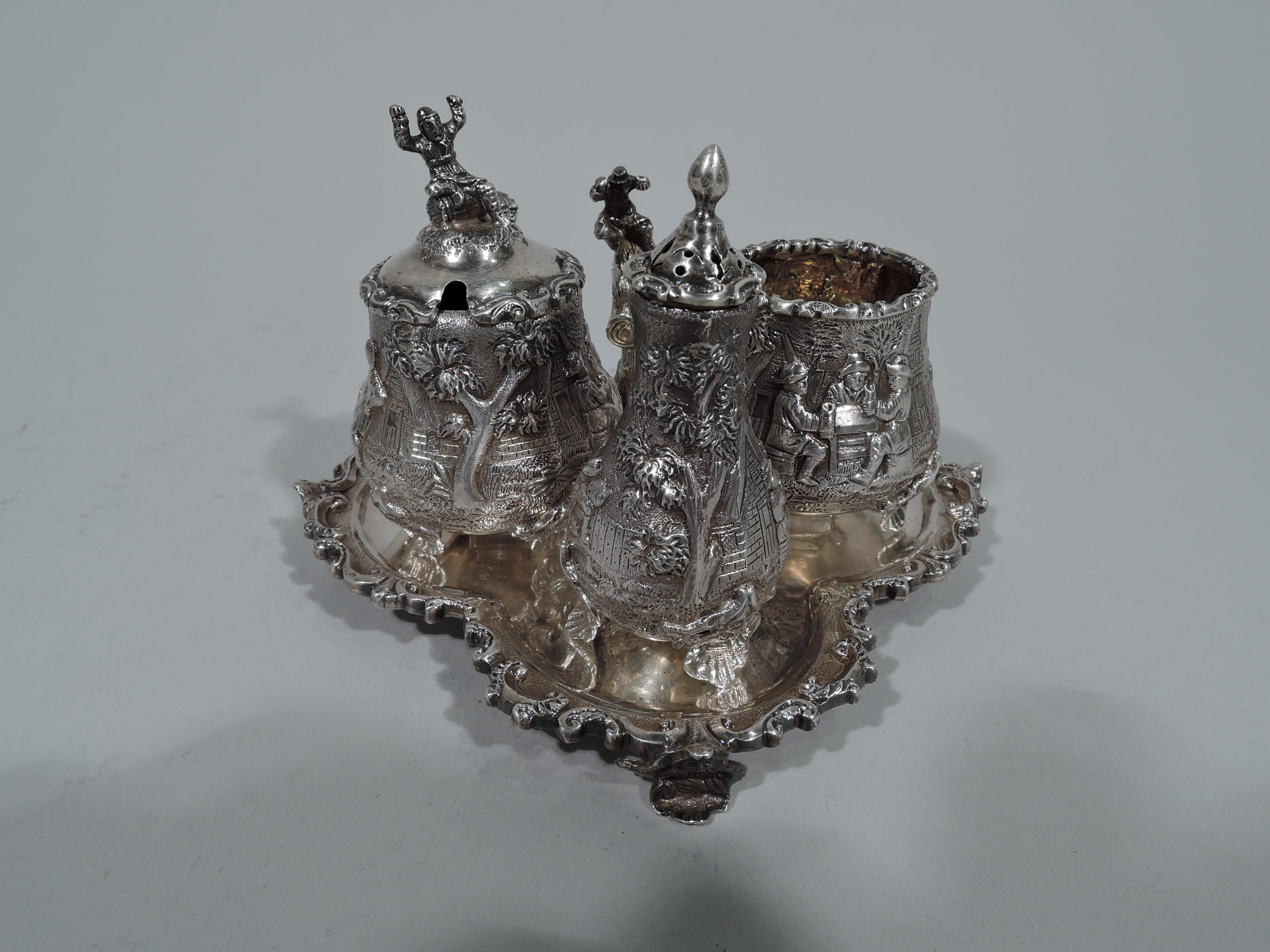 Victorian sterling silver condiment set. Made by George Fox in London in 1881. This set comprises mustard pot, open salt, and pepper shaker on stand. 

Mustard pot has hinged cover with twig scroll handle and figural finial of man seated on