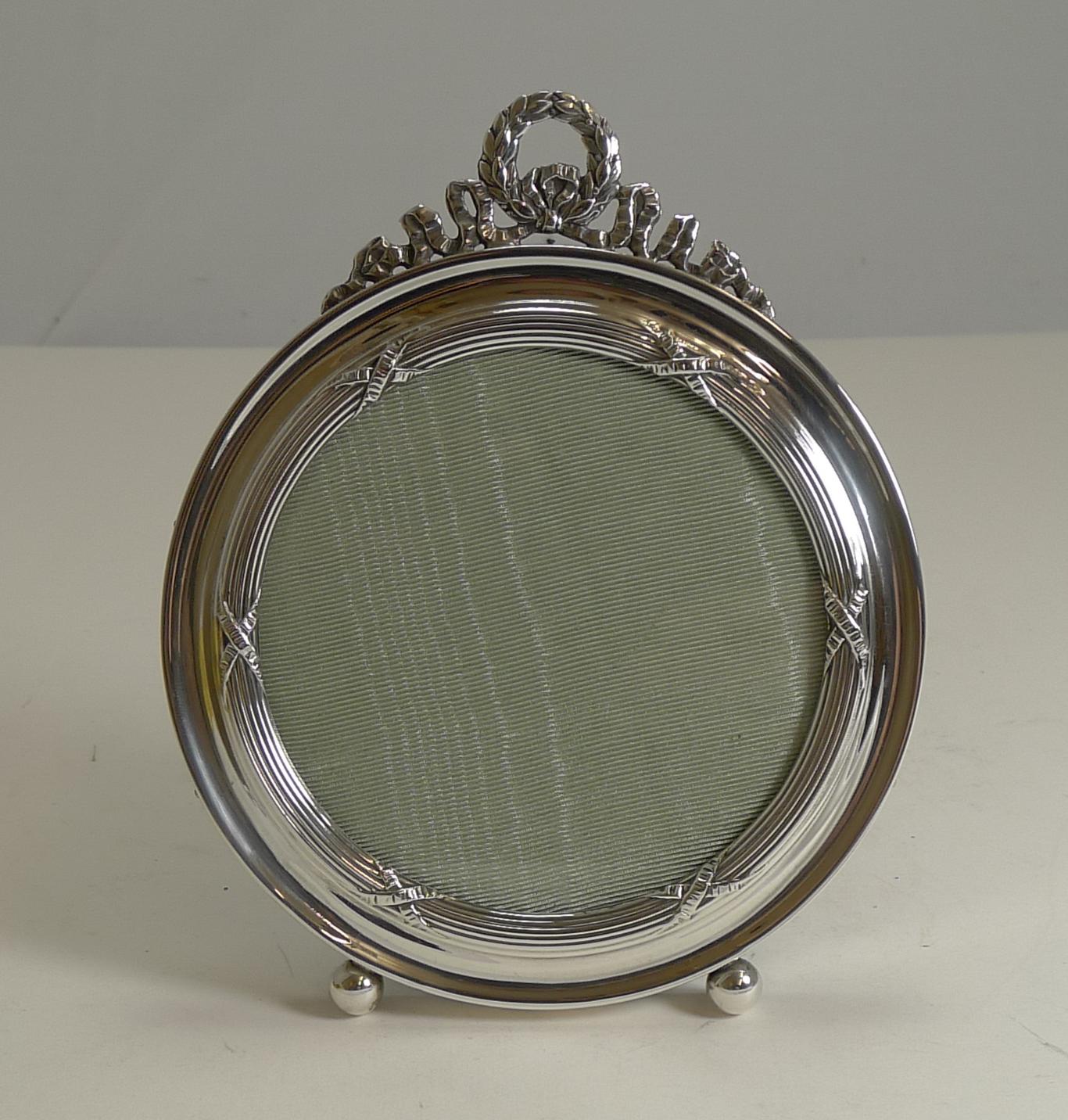 Pretty as a picture, the English Edwardian photograph frame is made from English sterling silver fully hallmarked for Birmingham 1909 together with the makers mark for the well renowned silversmith, Henry Matthews.

The circular frame is decorated
