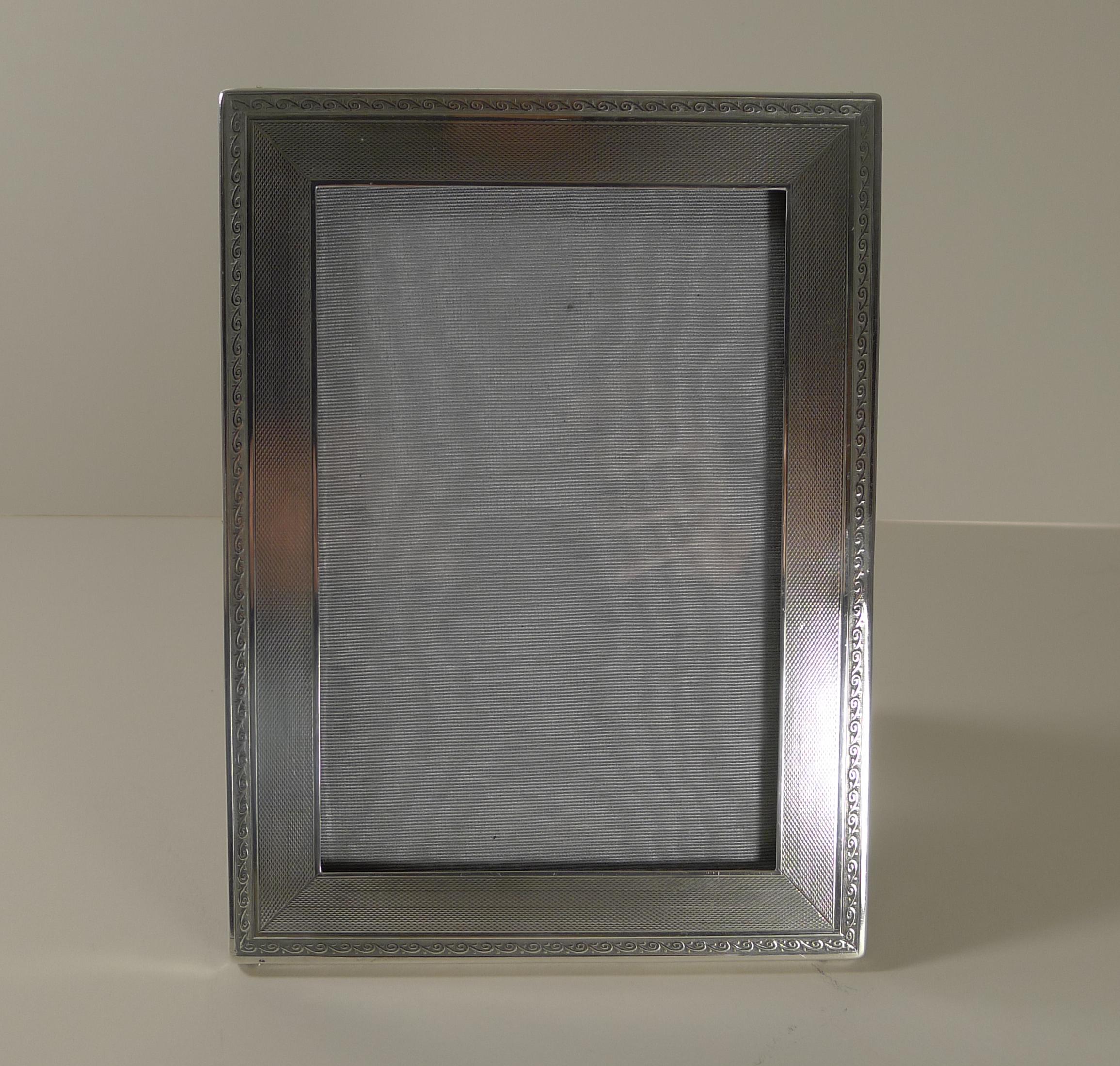 A fabulous Art Deco photograph frame, exactly 100 years old, making it a true antique example. The silver is beautifully decorated with an engine turned panel with a decorative border.

The backing is made from solid wood with a folding easel