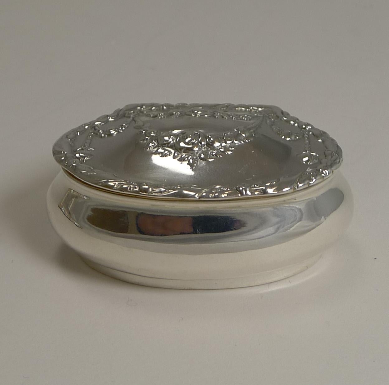 Pretty as a picture, this delightful sterling silver pill box with it's elegant shape and domed lid is adorned with a pretty floral garland decoration.

The lid fits well and once opened, reveals a lavishly gilded interior.

There is a full