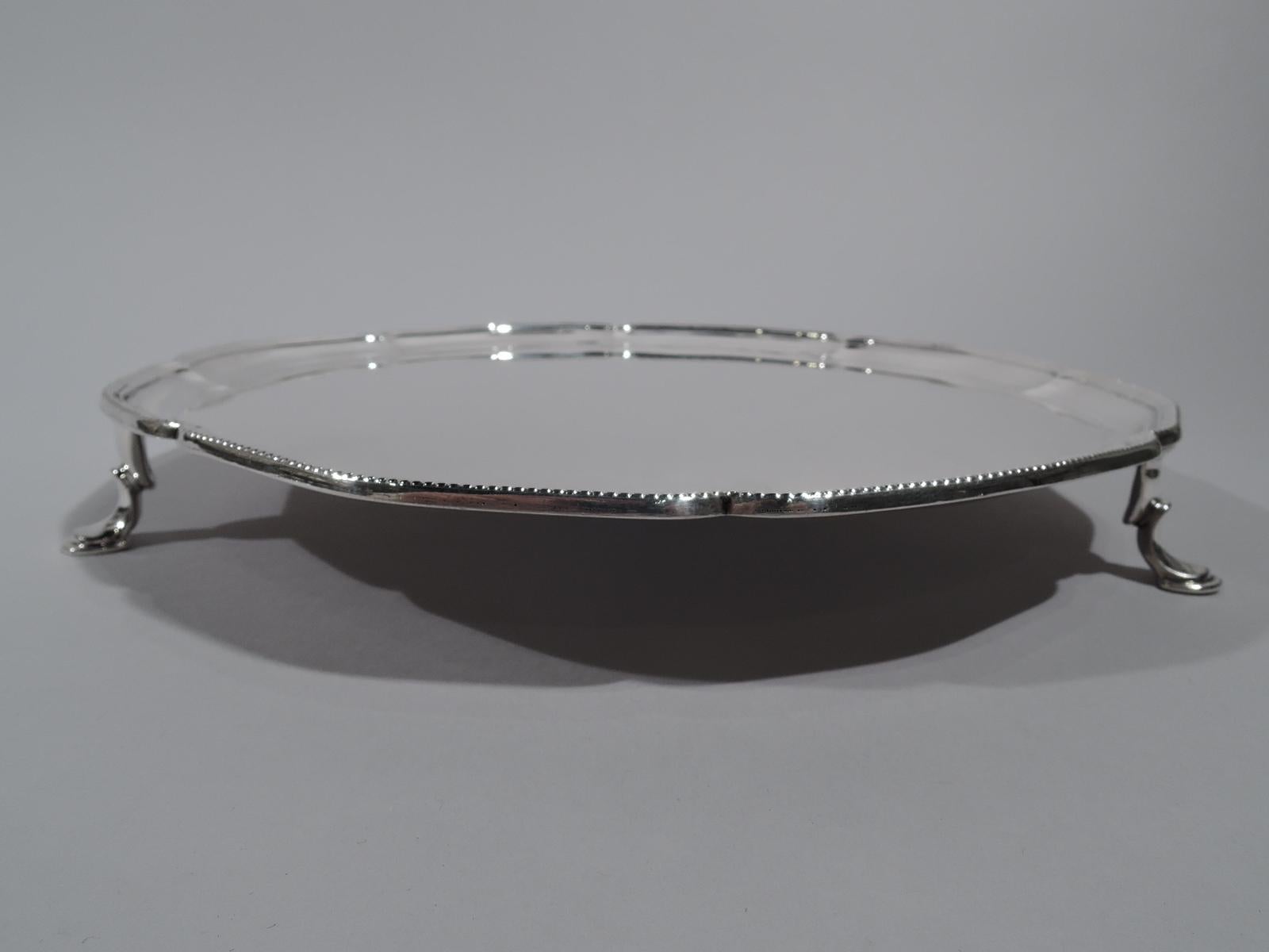 George V sterling silver salver. Made by Crichton in London in 1925. Round with beaded and shallow lobing. Rests on 3 padded C-scroll supports. Fully marked. Weight: 21 troy ounces.