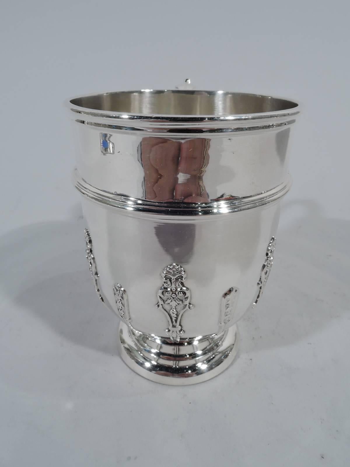 Victorian sterling silver baby cup. Made by Thomas, Walter & Henry Holland in London in 1896. Curved bottom, stepped foot, and leaf-capped double-scroll handle. Molded rim and applied band. Vertical strapwork with flowers and scrolls on stippled