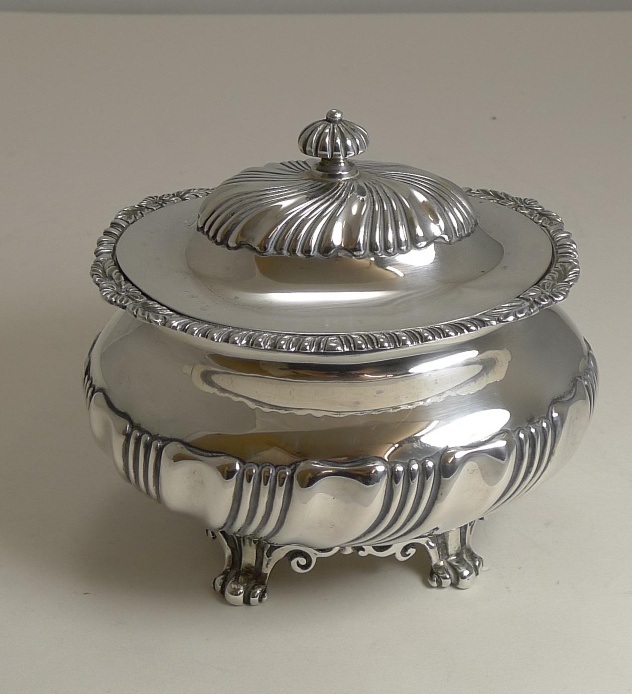 A stunning large and heavy tea caddy standing on pierced or reticulated cast base incorporating four feet, a fluted decoration to the body, hinged lid and finial; and an attractive cast border around the top of the caddy.

The silver is fully
