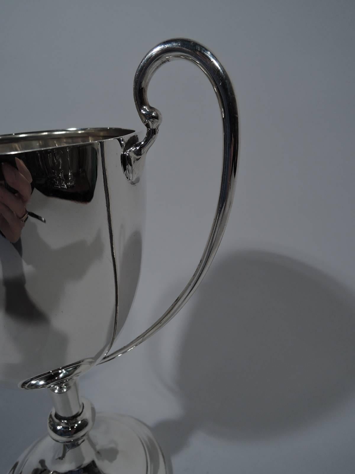 George V sterling silver trophy cup. Made by Barker Bros, Ltd in Birmingham in 1932. Ovoid bowl with high-looping scroll handles, knopped cylindrical stem, and stepped foot. A classic design with plenty of room for engraving. Hallmarked. Weight: 11