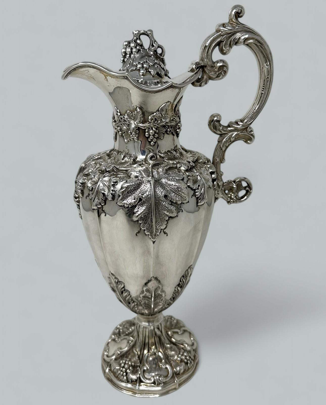 Una squisita brocca da vino da tavolo in stile Regency inglese, vittoriana, in argento sterling di calibro pesante e dai contorni tradizionali. 

La decorazione del corpo a foglie di vite si trova al di sotto di un coperchio a cerniera con un