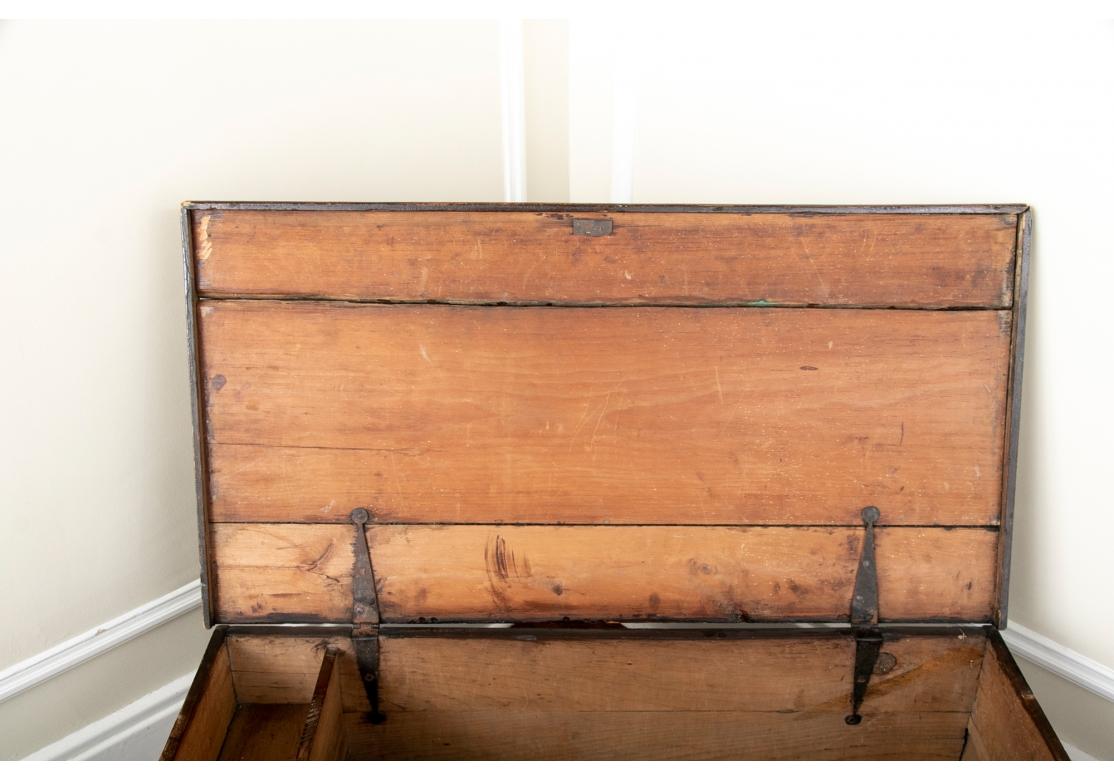 A plank constructed trunk on a carved base. The lid with a fine sailing ship in an oval, the front with label VR (for Victoria Regina) and L.B. Gunner 1811, B. Deck with illustration of a cannon along with British flags. The inside with iron hinges