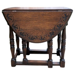 Ancienne table anglaise en chêne sculpté avec pieds de chevalet tournés et accoudoirs en forme de feuille et plateau ovale