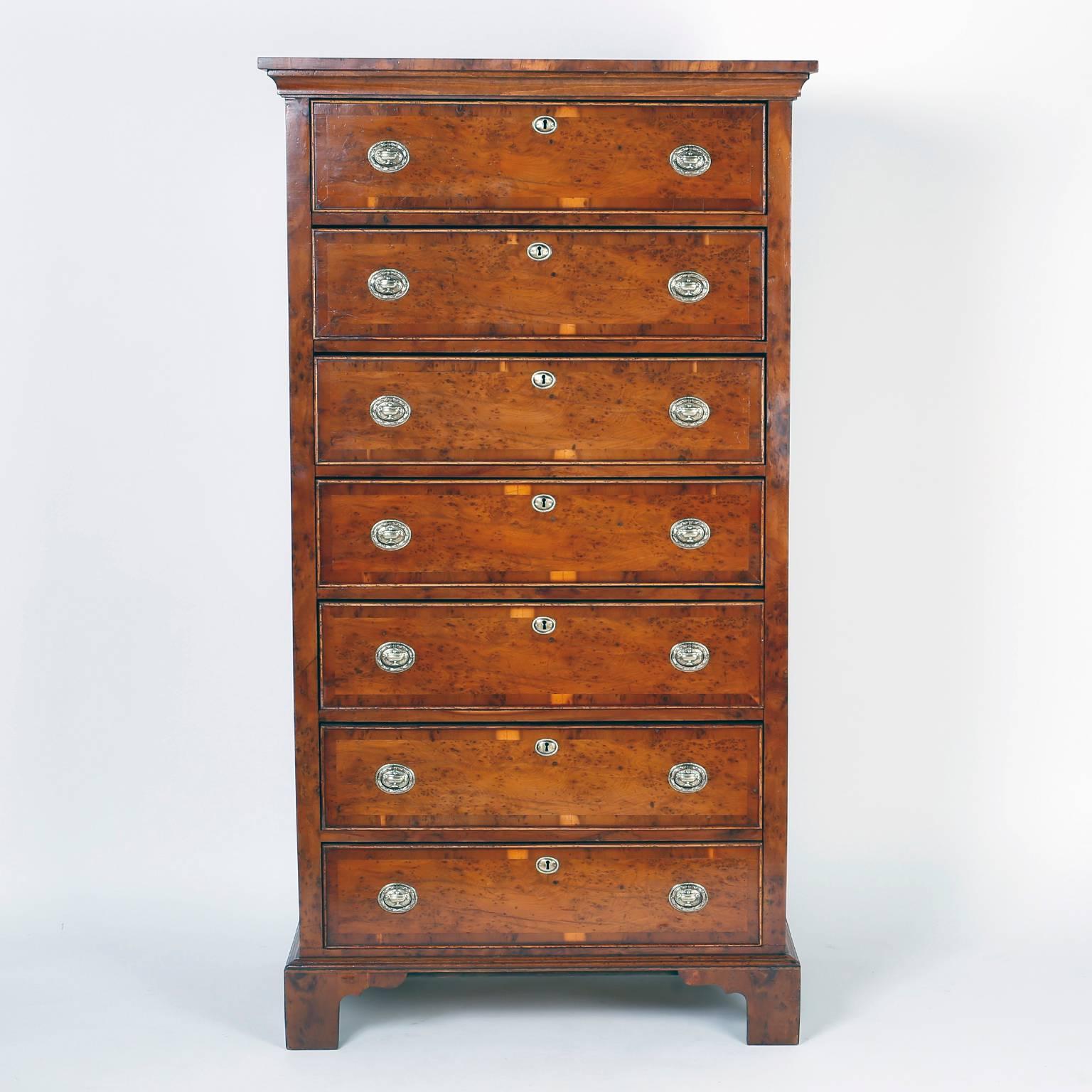 Handsome English gentlemen's chest with seven drawers featuring rare
and exotic yew wood veneers, brass hardware panelled sides and outside bracket
feet. The elegant form and dramatic wood grains make this chest an
important find.