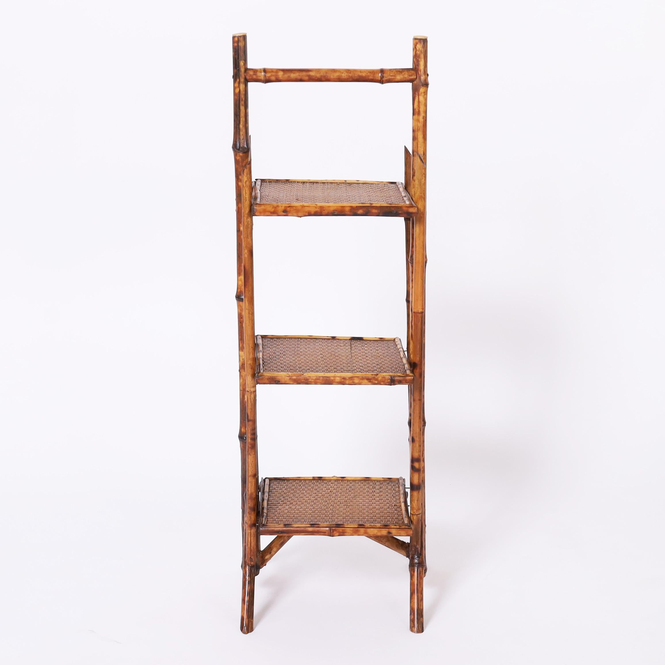 Stand inglese del XIX secolo realizzato a mano in bambù con finitura in finta tartaruga bruciata, con tre livelli ricoperti di canne intrecciate. 