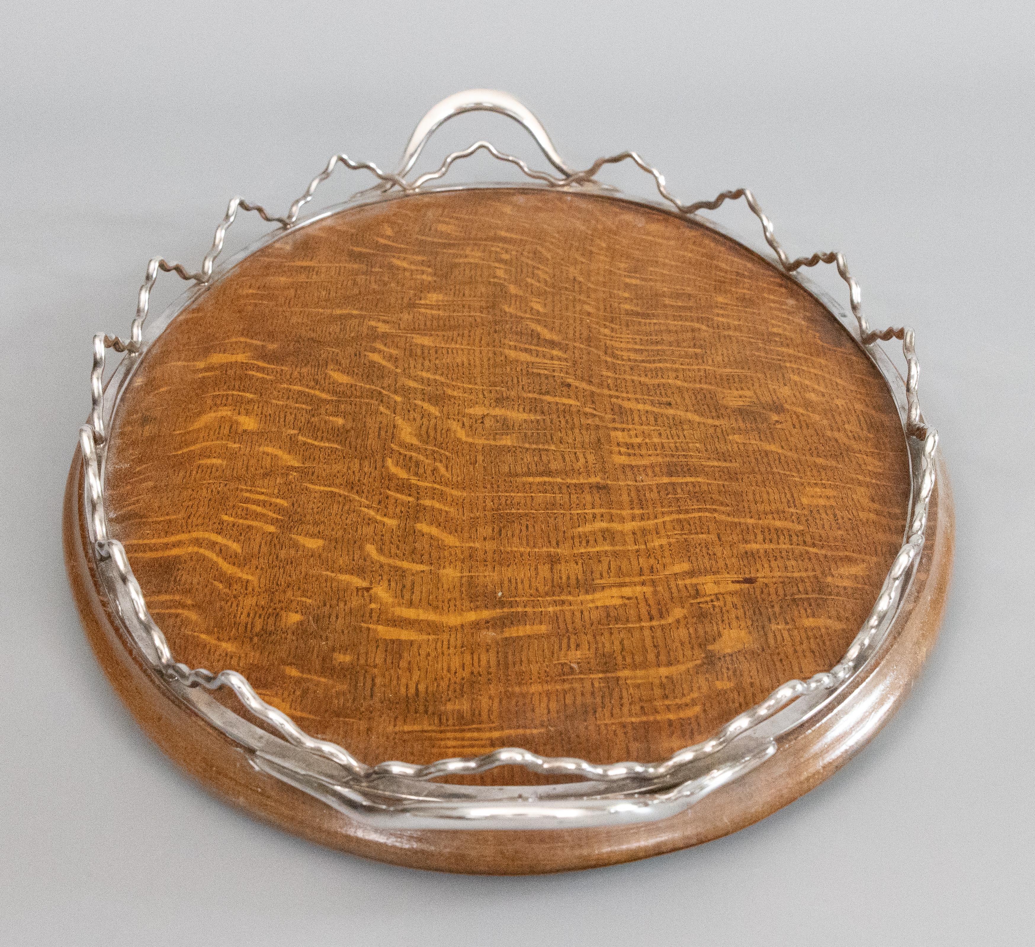 A fine antique English tiger oak oval serving tray with a rare wavy silver plate gallery on four bun feet, circa 1900. Hallmarked on handle. The original surface and patina add character to this stunning tray, which would be perfect for serving or
