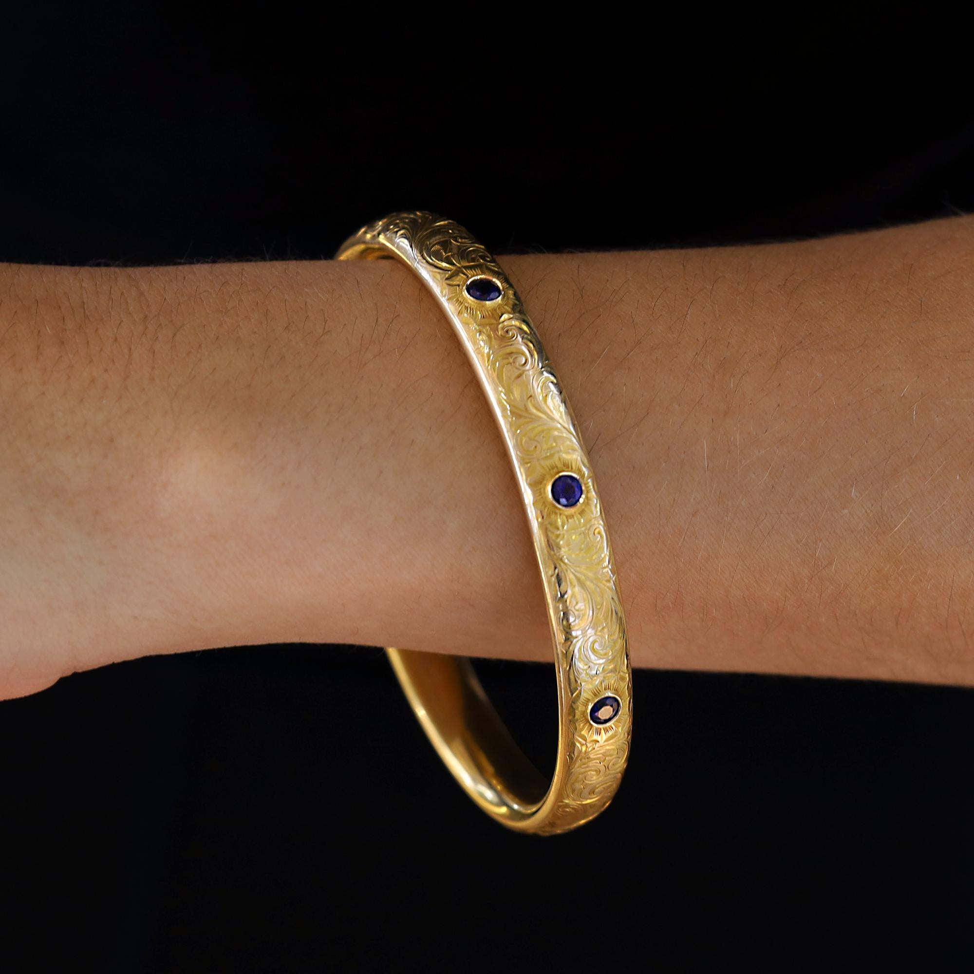Infila questo antico braccialetto inglese vittoriano al polso e trasportati alla fine del XIX secolo. Un'elegante incisione fogliare circonda il ricco oro giallo 16 carati insieme a un trio di vibranti zaffiri blu. Eleva la tua pila da polso con