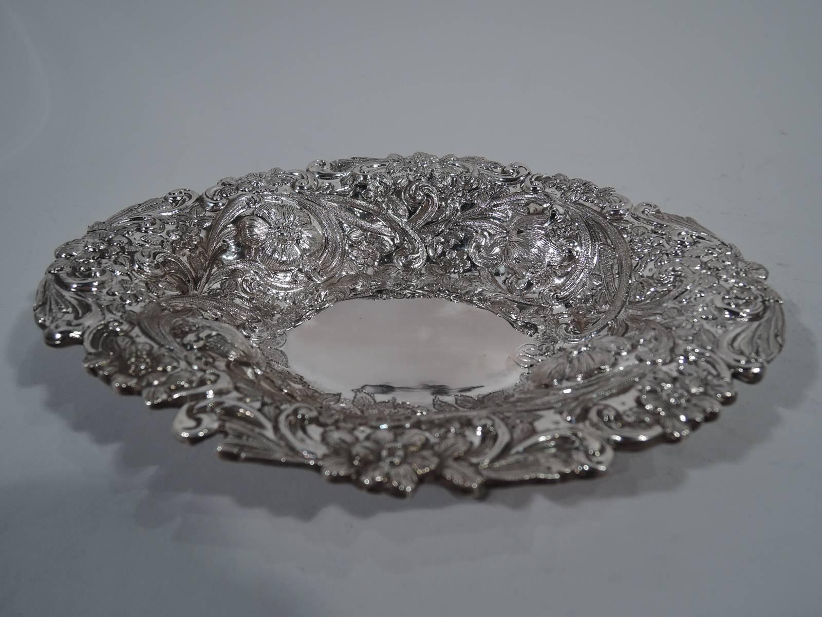 Victorian sterling silver bowl. Made by William Gibson & John Langman in London in 1888. Plain and ovalish well, tapering sides, and irregular rim. Dense repousse ornament heightened with engraving: Traditional floral ornament embedded with big bold