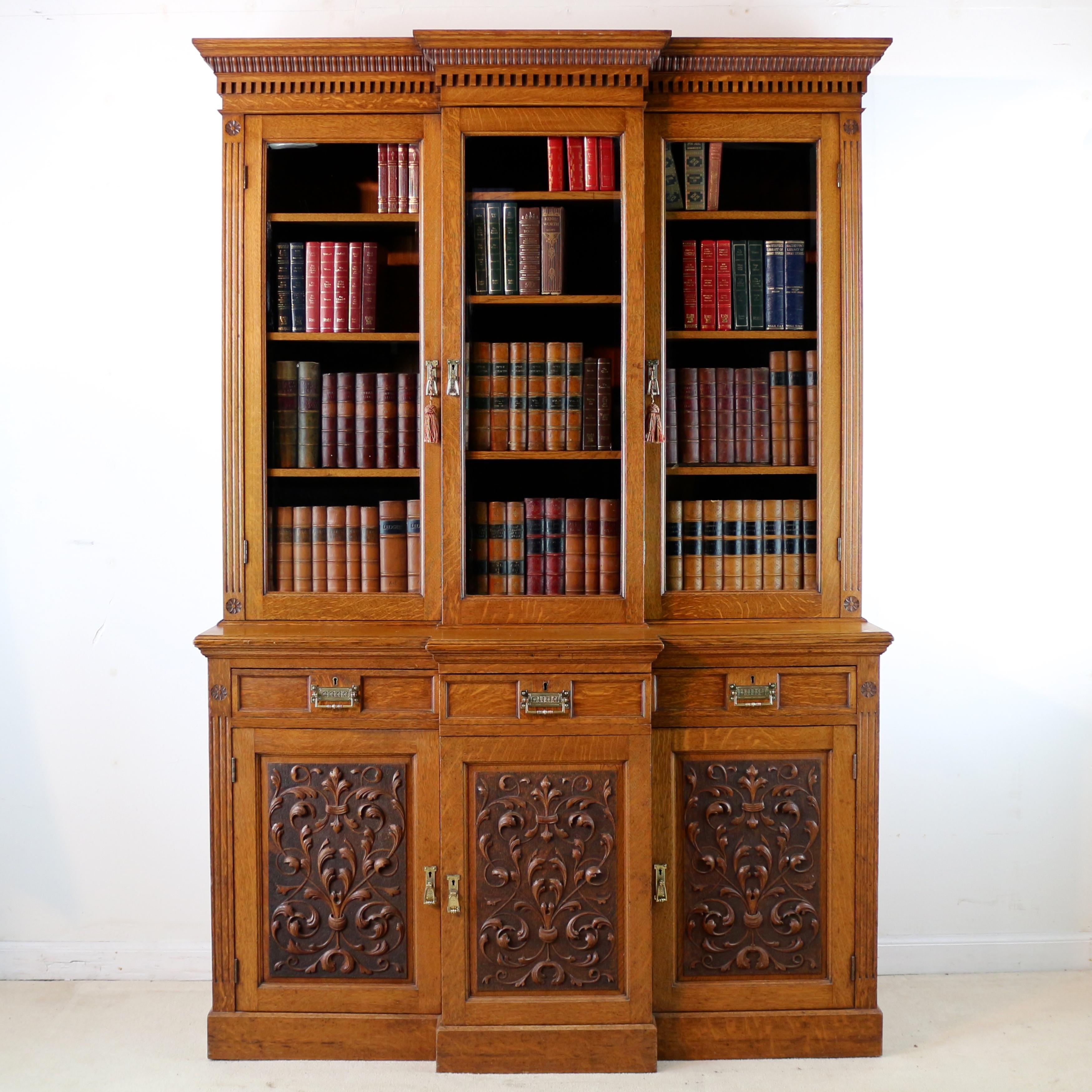 A beautiful Victorian three door breakfront bookcase or display cabinet attributed to Maple & Co and in the Art Nouveau/Arts & Crafts taste. In golden quarter-sawn oak with bevelled glass panes to the glazed doors it features a reeded and dentil